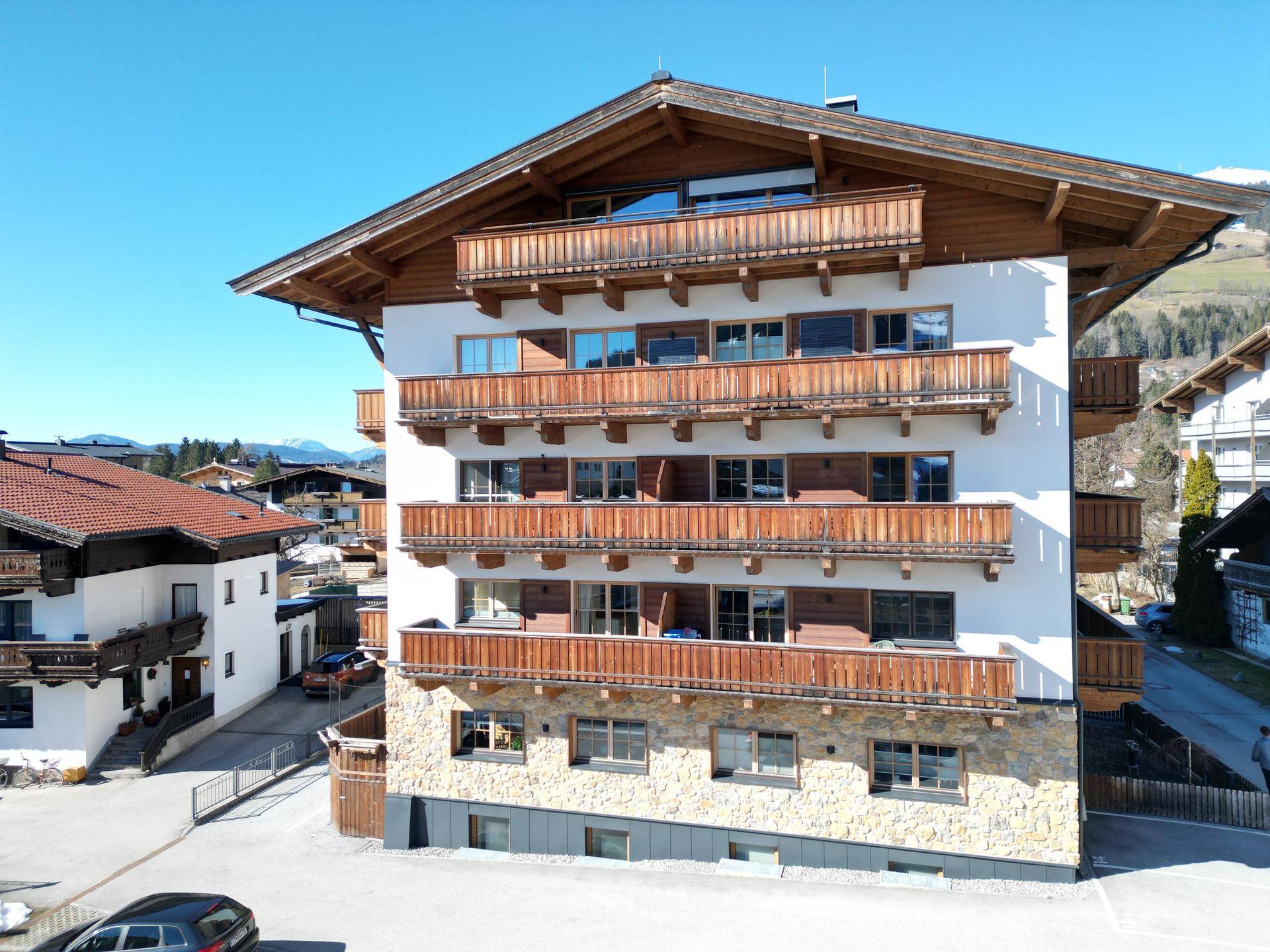 Alpines Wohngebäude mit traditionellen Holzbalkonen und Blick auf die umliegende Berglandschaft.