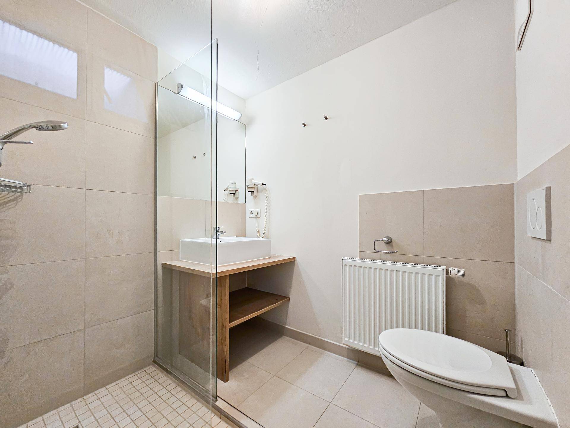 Modernes Badezimmer mit ebenerdiger Dusche, Waschtisch und hellen Fliesen.