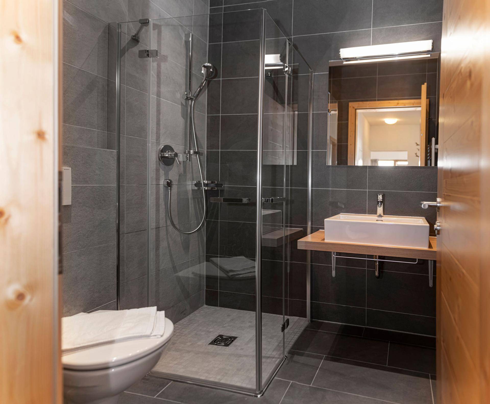 Elegantes Badezimmer mit ebenerdiger Dusche, WC und modernem Waschbecken.