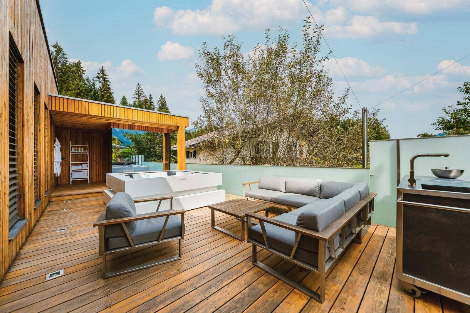 Geräumige Holzterrasse mit Lounge-Möbeln und Whirlpool, ideal für Entspannung im Freien.