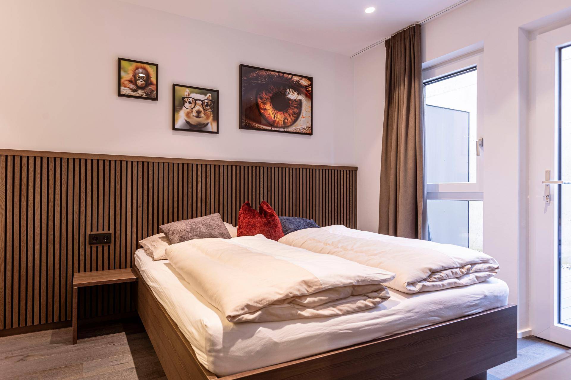 Schlafzimmer mit Doppelbett, Holzvertäfelung und Fenster mit Blick nach draußen.