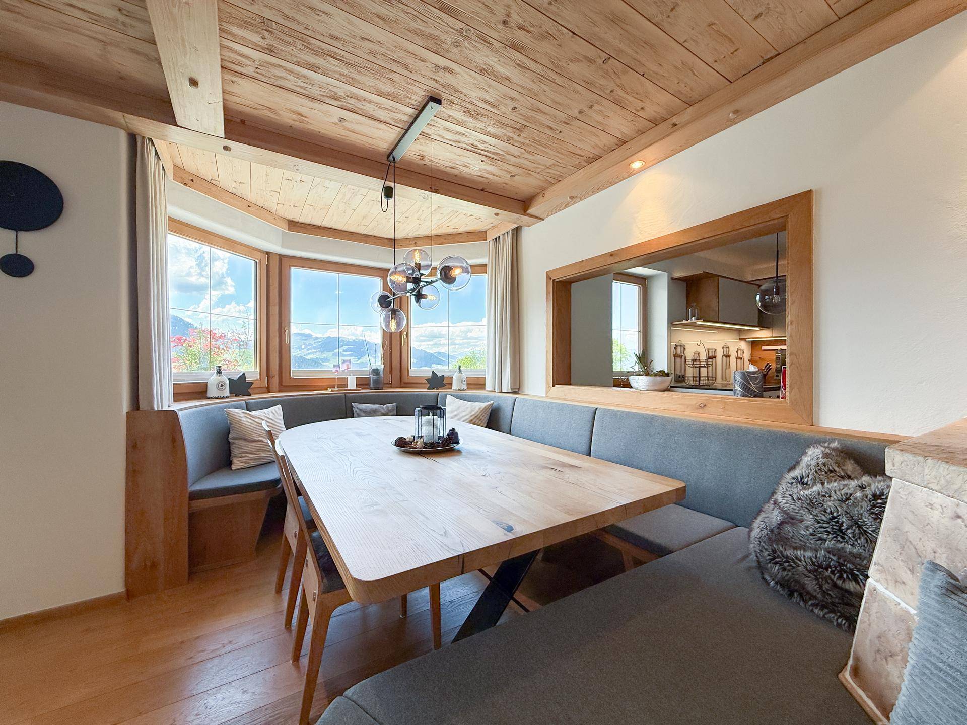 Gemütlicher Essbereich mit Holztisch, Eckbank und großen Fenstern mit Bergblick.