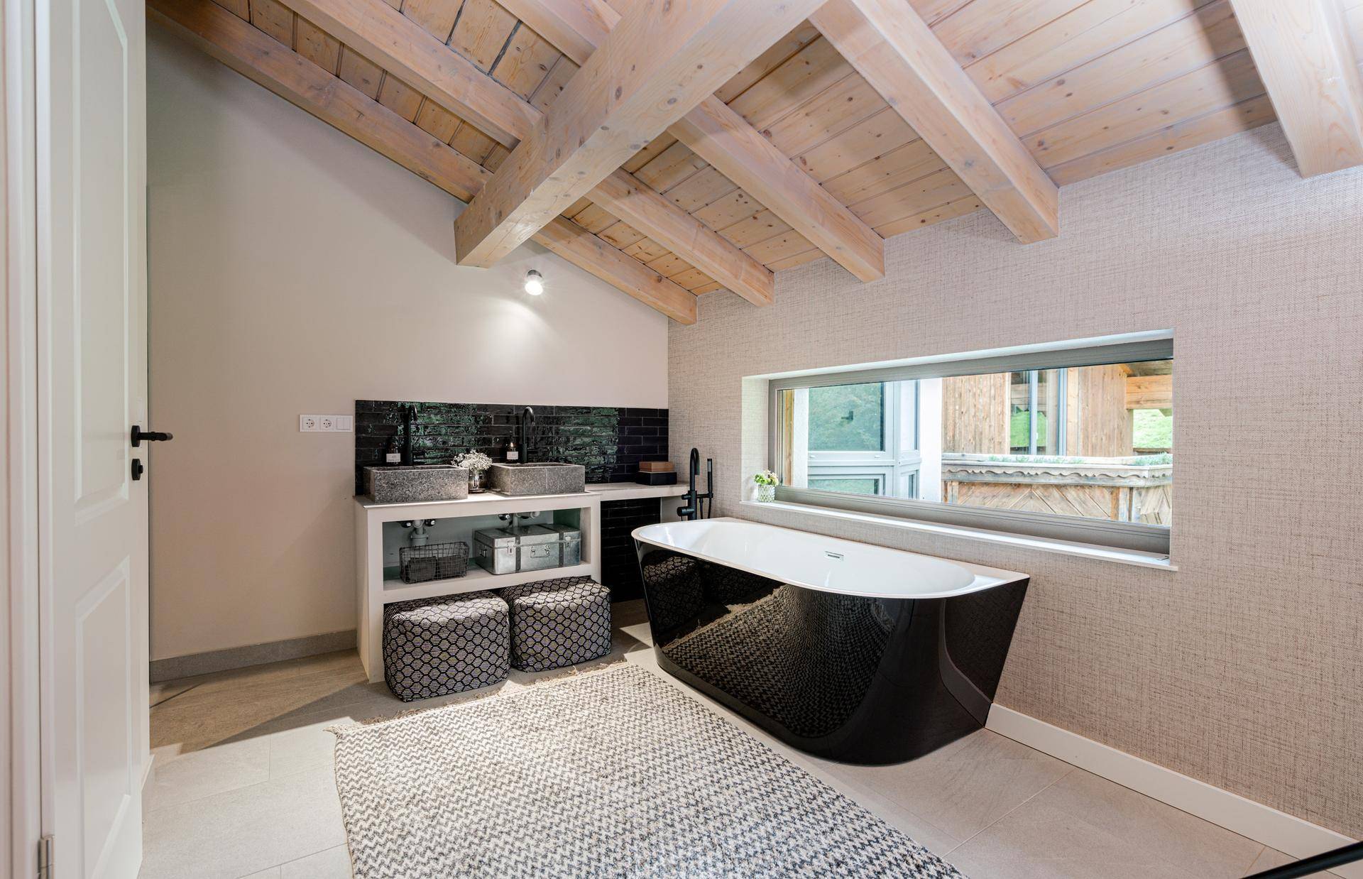 Geräumiges Badezimmer mit Doppelwaschbecken, freistehender Badewanne und Fenster mit Ausblick.