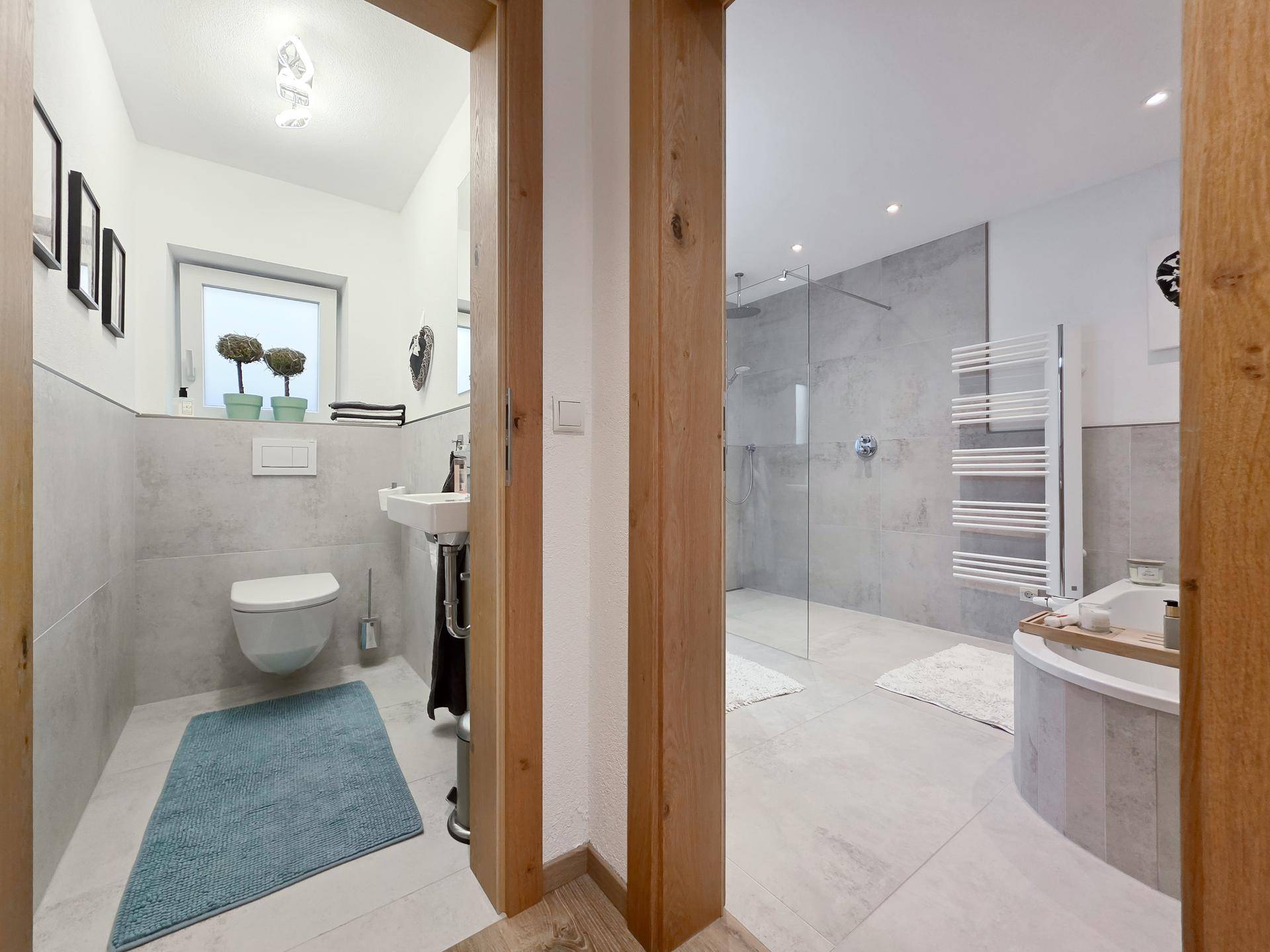 Helles Badezimmer mit begehbarer Dusche und separatem Gäste-WC, beide modern gefliest.