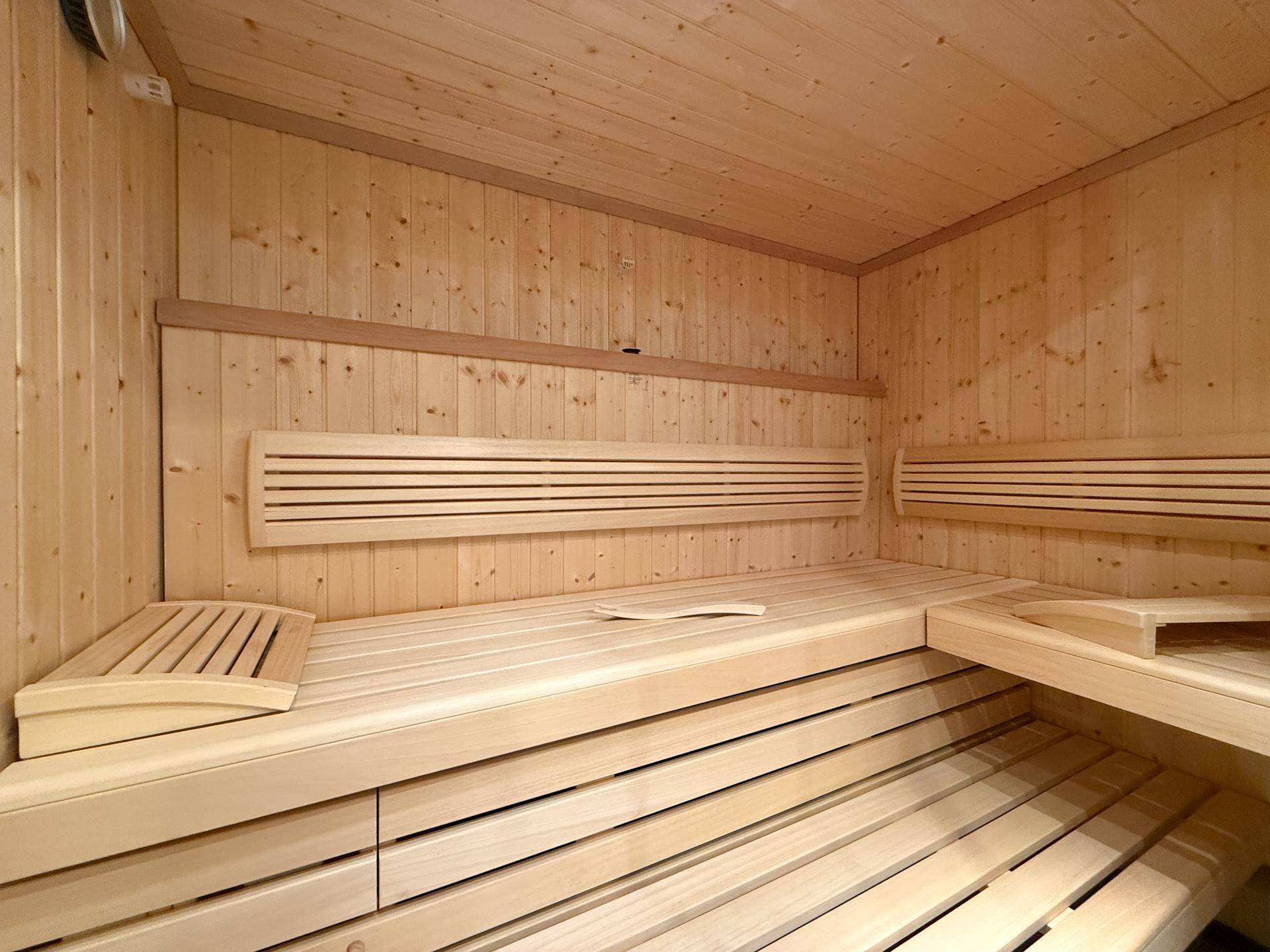 Gemütliche Sauna mit Holzverkleidung und bequemen Sitzbänken für Entspannung.