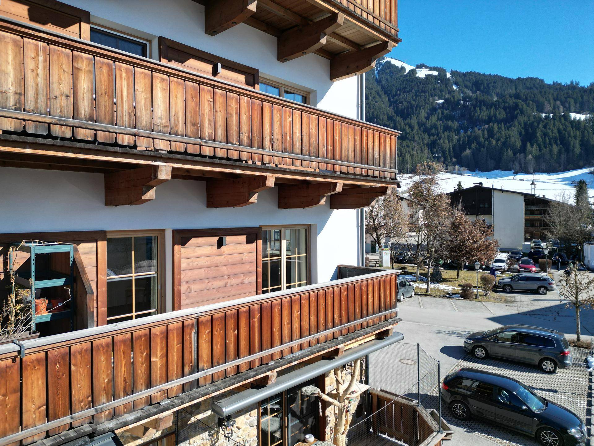 Detailansicht der Holzbalkone mit Blick auf die verschneite Bergwelt und die Straße.