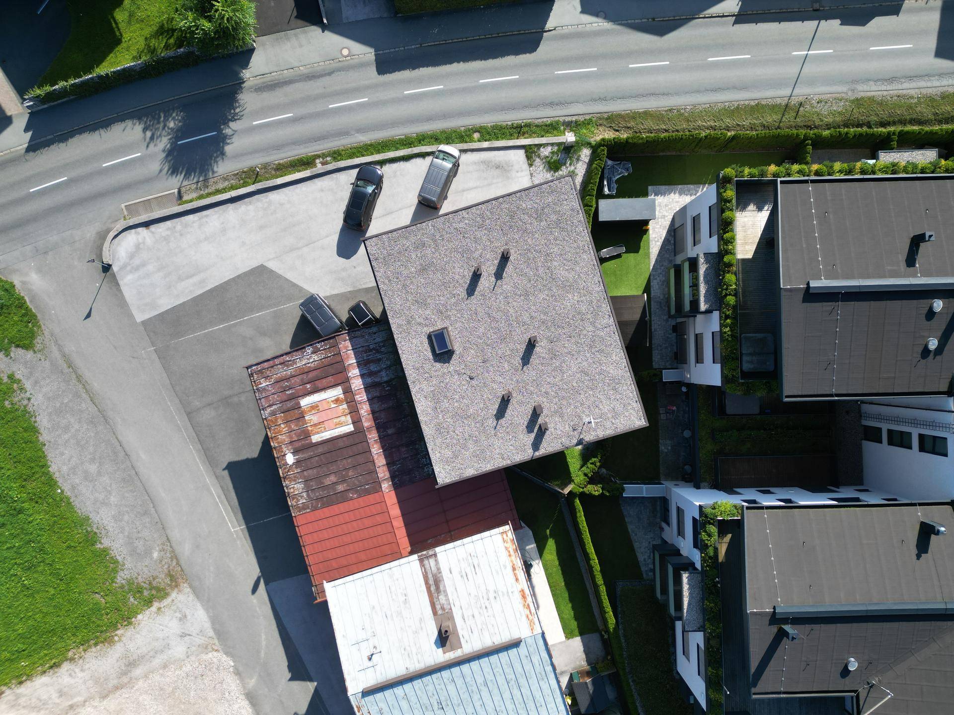 Draufsicht auf das Gebäude mit Flachdach, Parkplätzen und angrenzenden Grundstücken.