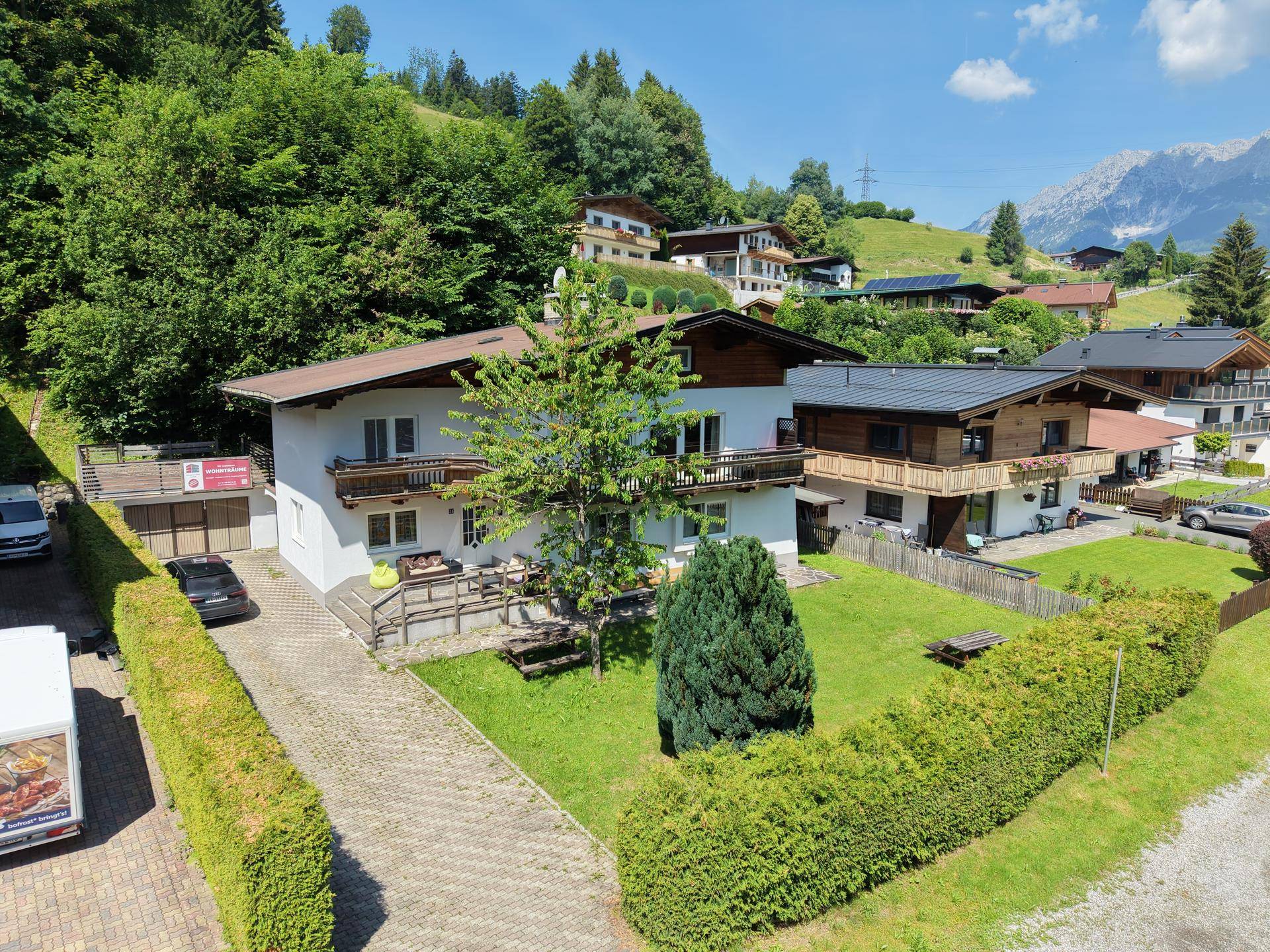 Ansicht des Hauses mit Einfahrt, Gartenbereich und gemütlicher Sitzecke im Freien.