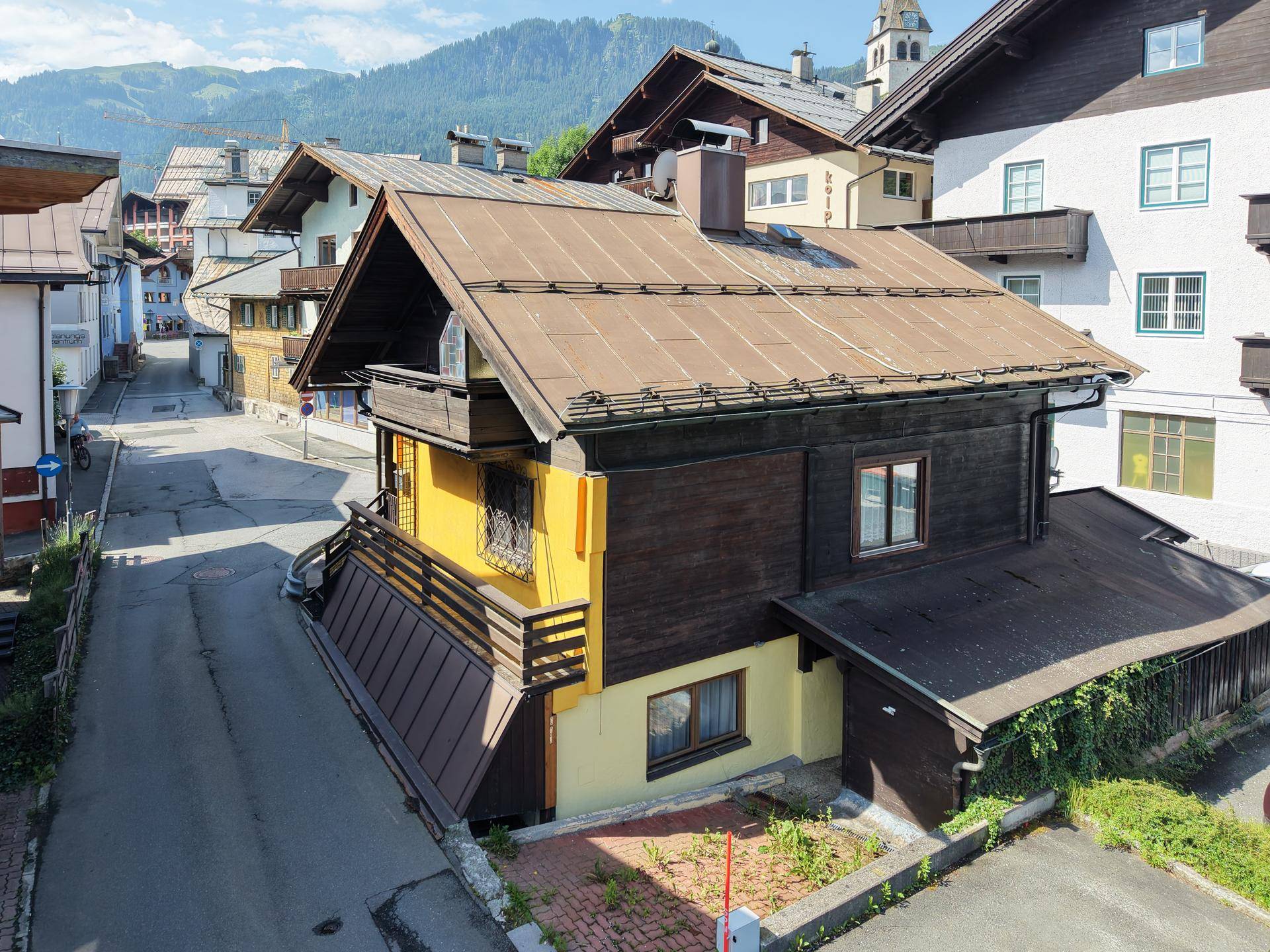 Rückansicht eines traditionellen Hauses mit gelber Fassade und Holzbalkonen in einer Gasse.