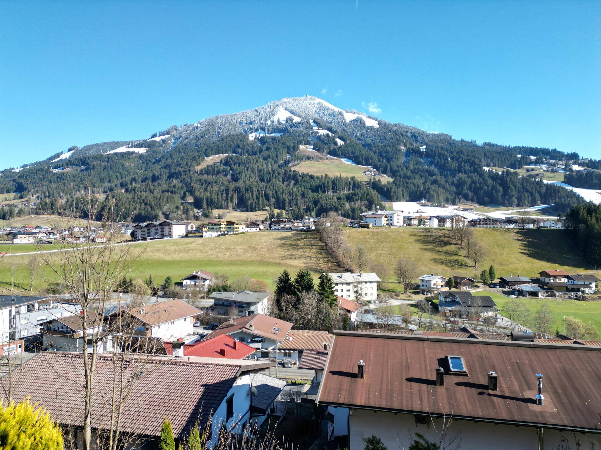 Panoramablick auf eine schneebedeckte Berglandschaft mit Häusern im Tal.