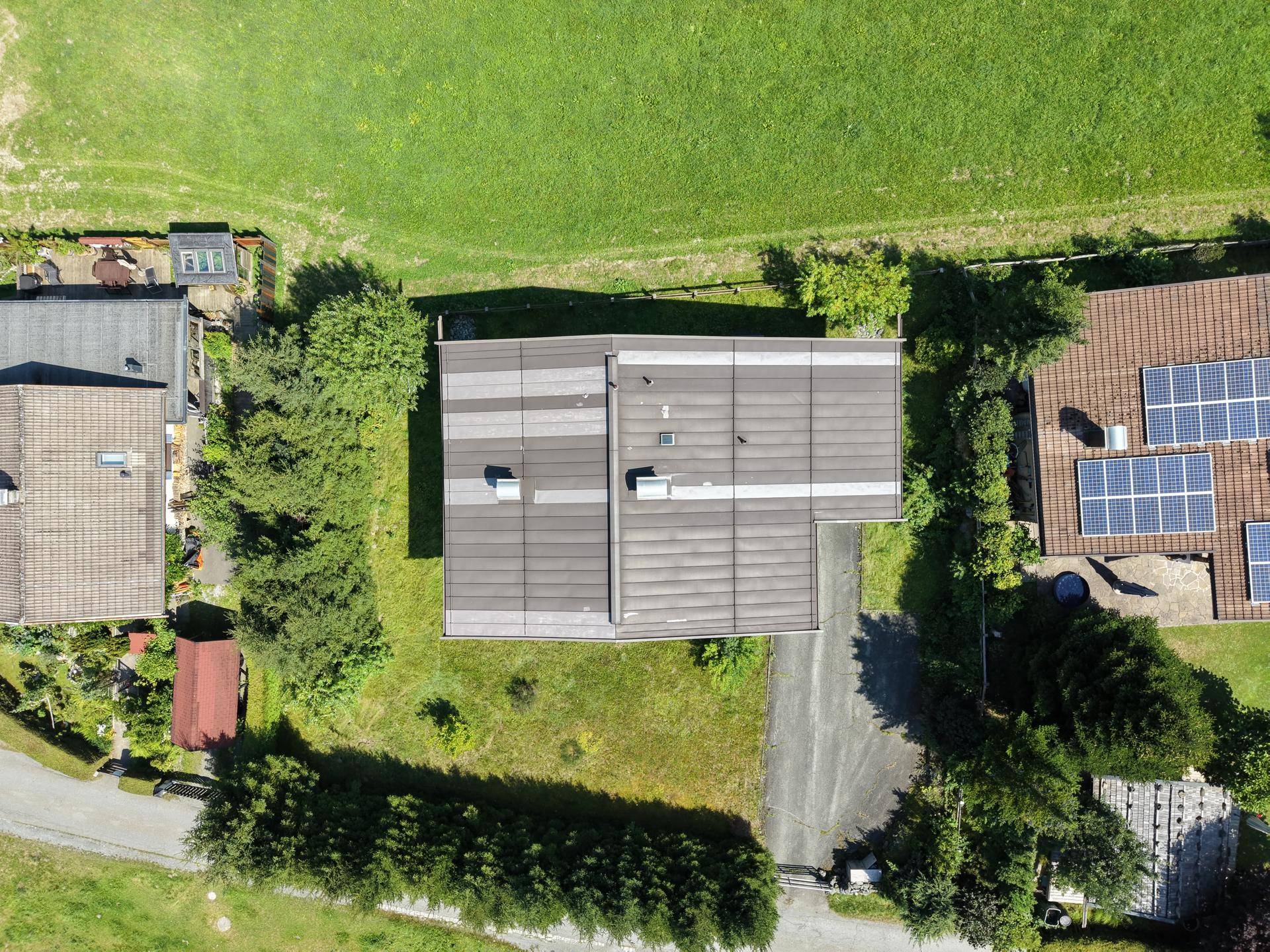 Draufsicht des Hauses mit Satteldach, umgeben von Rasenflächen und angrenzenden Grundstücken.