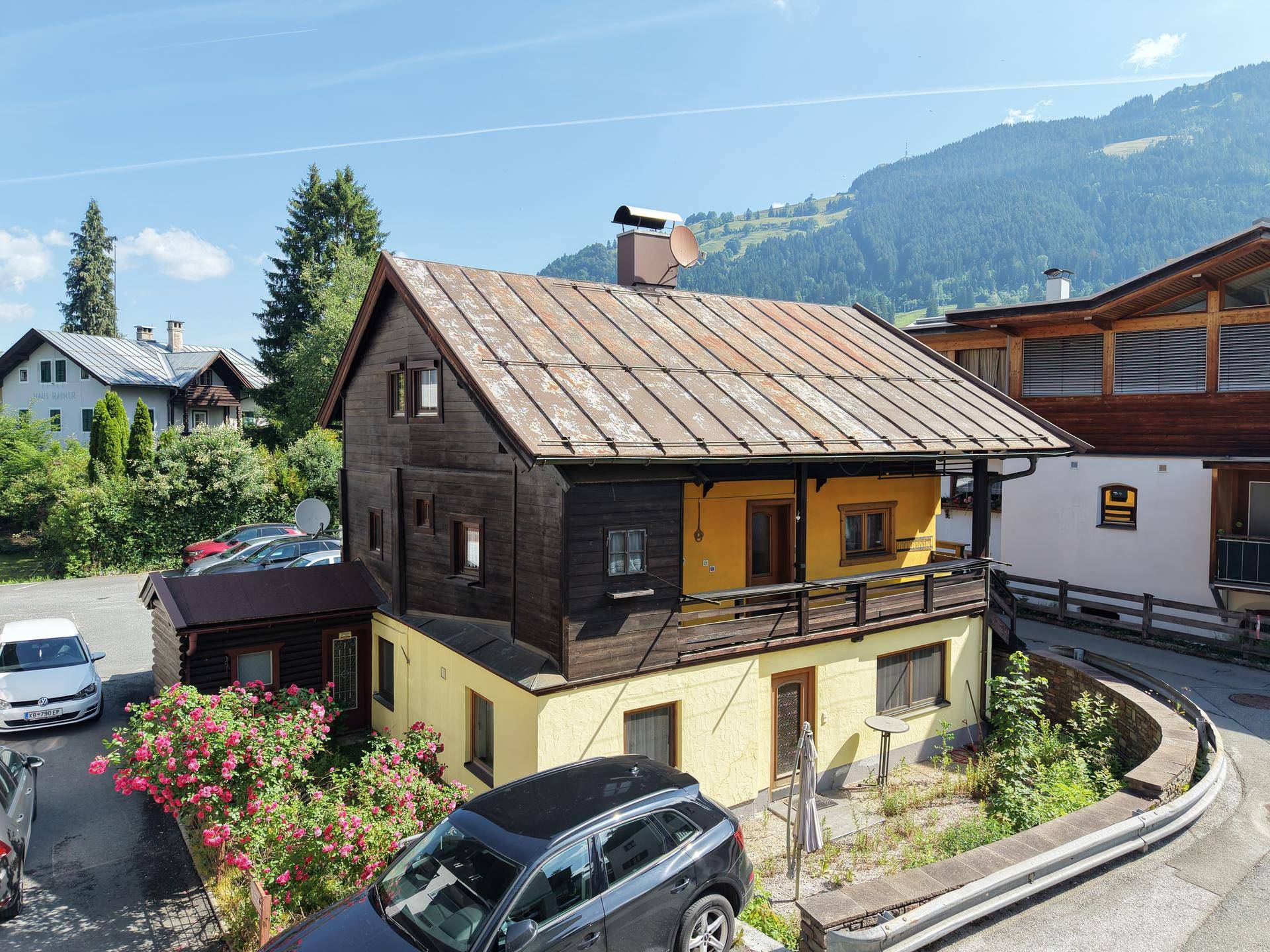Traditionelles Haus mit gelber Fassade und Holzelementen in alpiner Umgebung mit Bergblick.