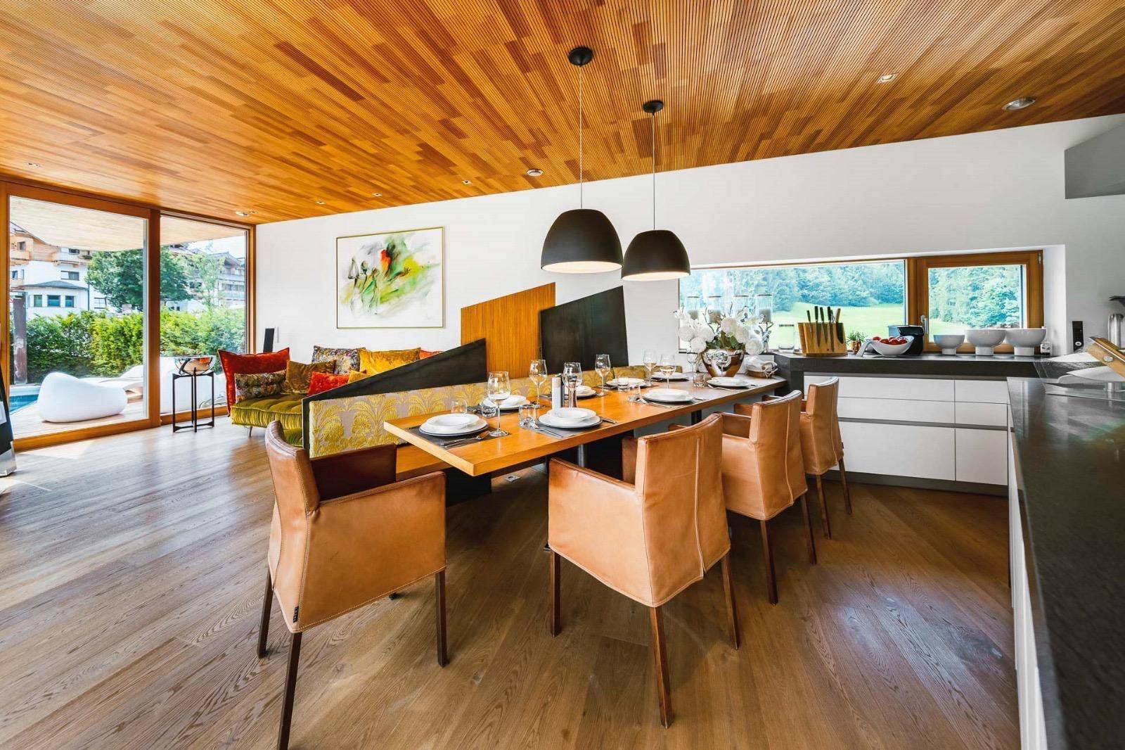 Eleganter Essbereich mit Holztisch und Ledersesseln, integriert in den offenen Wohn- und Küchenbereich.