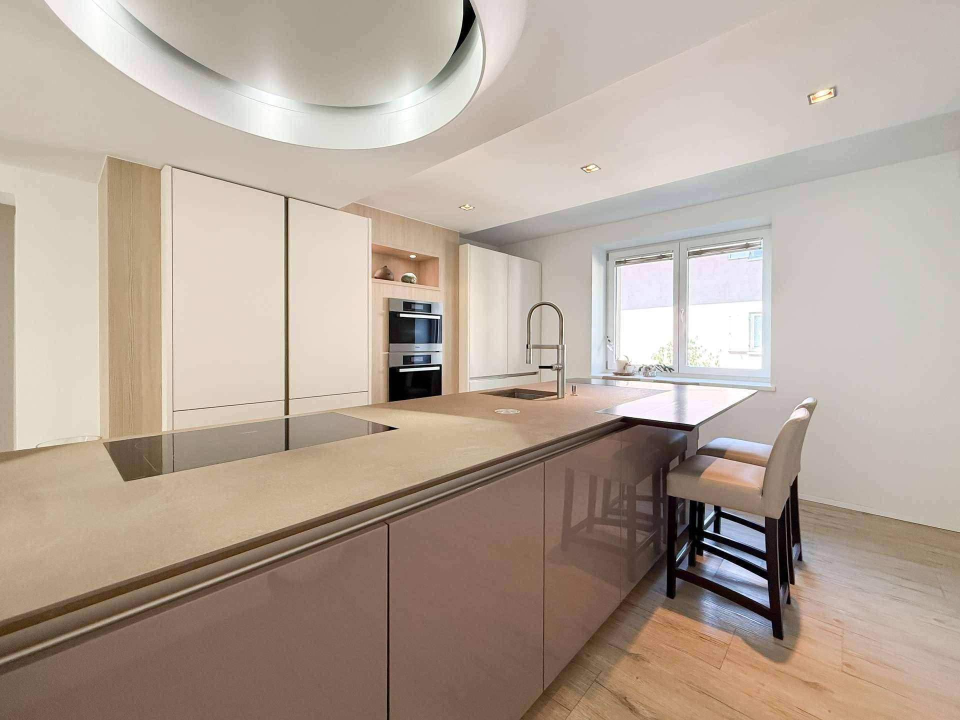 Moderne Küche mit großer Kücheninsel, integrierten Geräten und hellem Design.