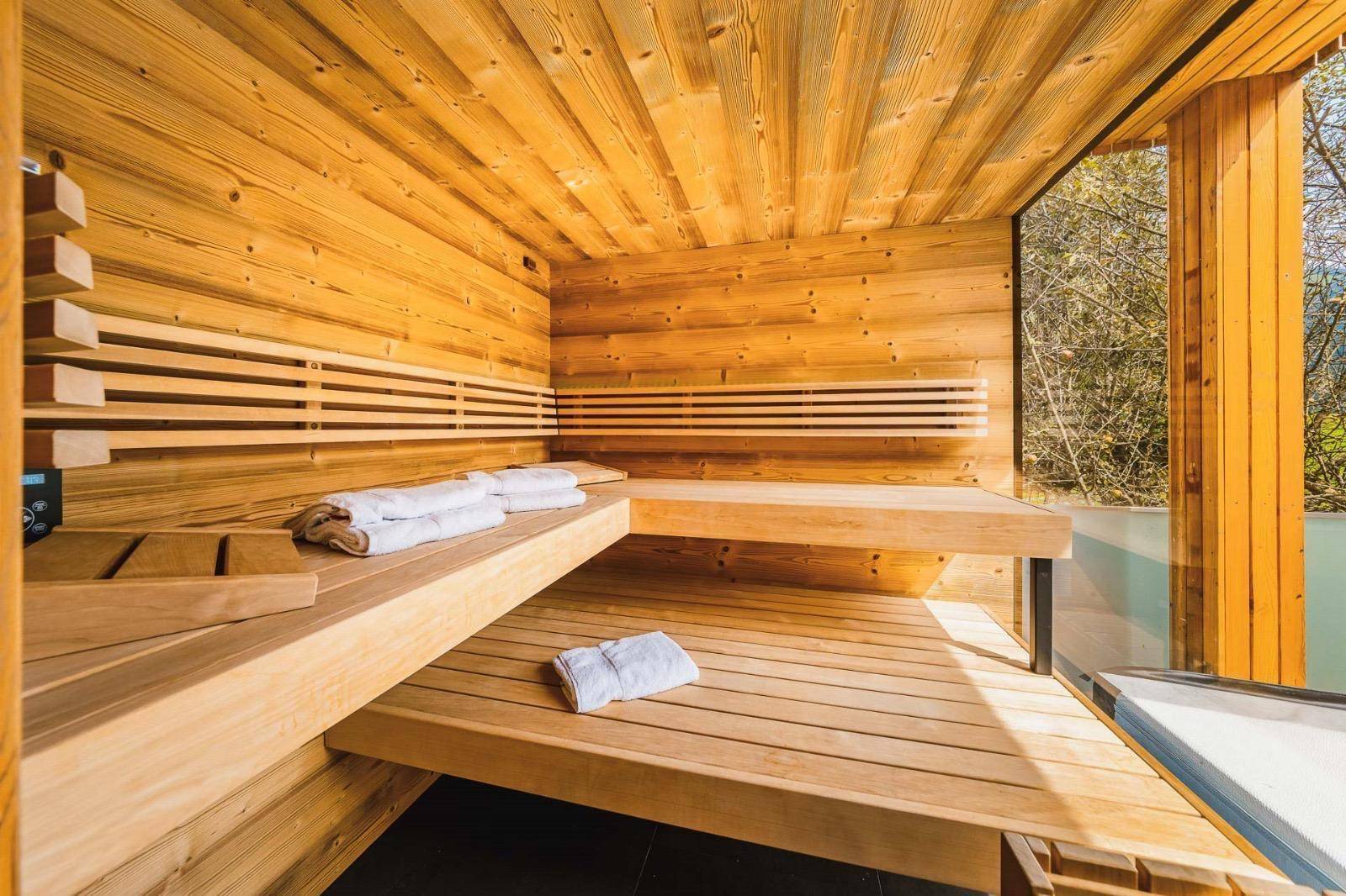 Helle Holzsauna mit großen Fenstern und Blick ins Grüne, ideal zur Entspannung.