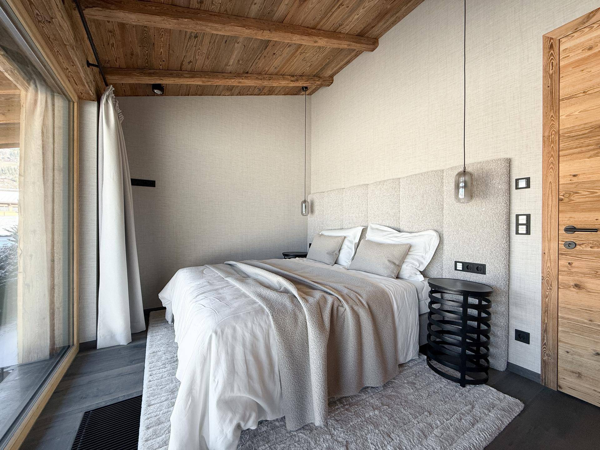 Geräumiges Schlafzimmer mit Holzbalkendecke, modernem Design und viel natürlichem Licht.