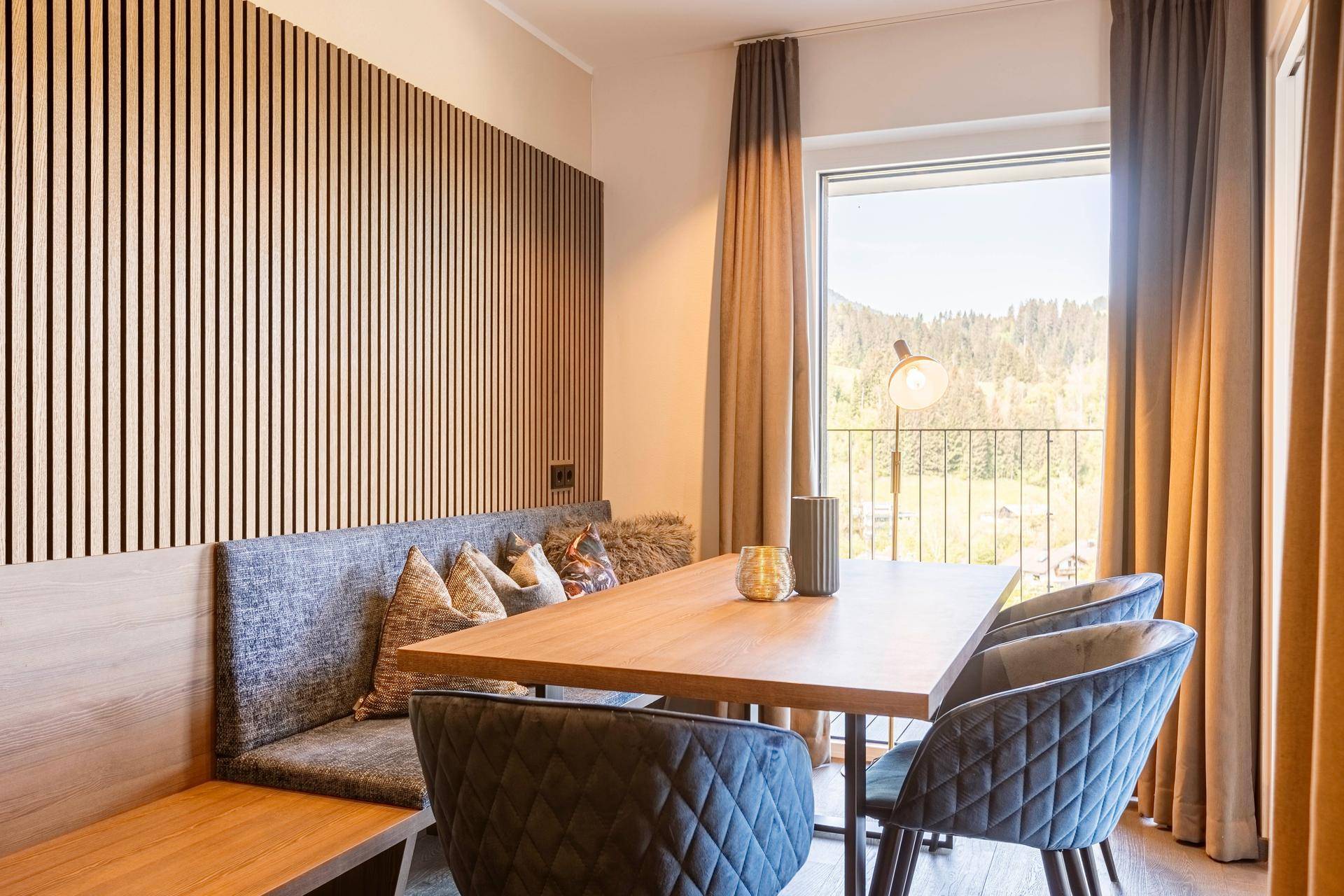 Moderner Essbereich mit Holztisch und gepolsterter Sitzbank, umgeben von Holzlamellen.