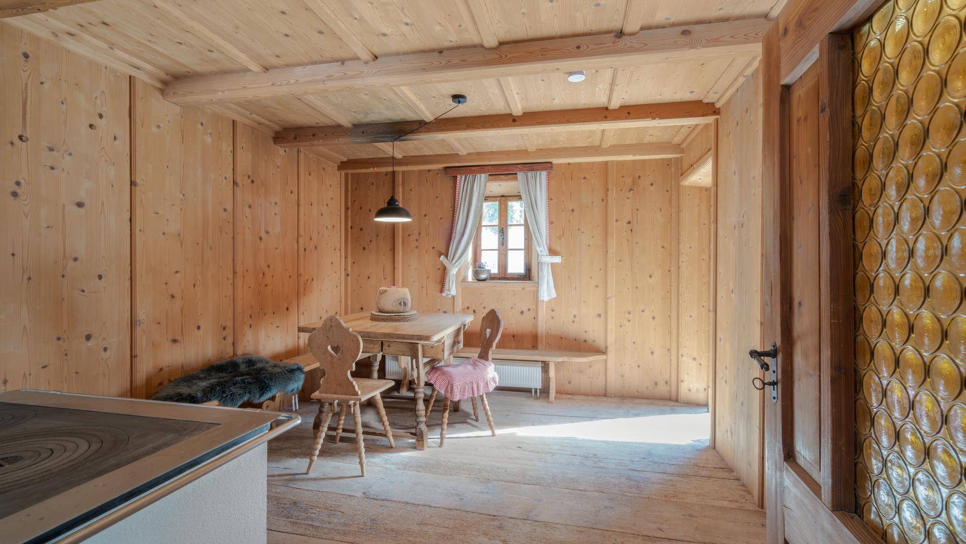 Rustikaler Essbereich mit Holztäfelung, Holzboden und traditionellen Möbeln im alpinen Stil.