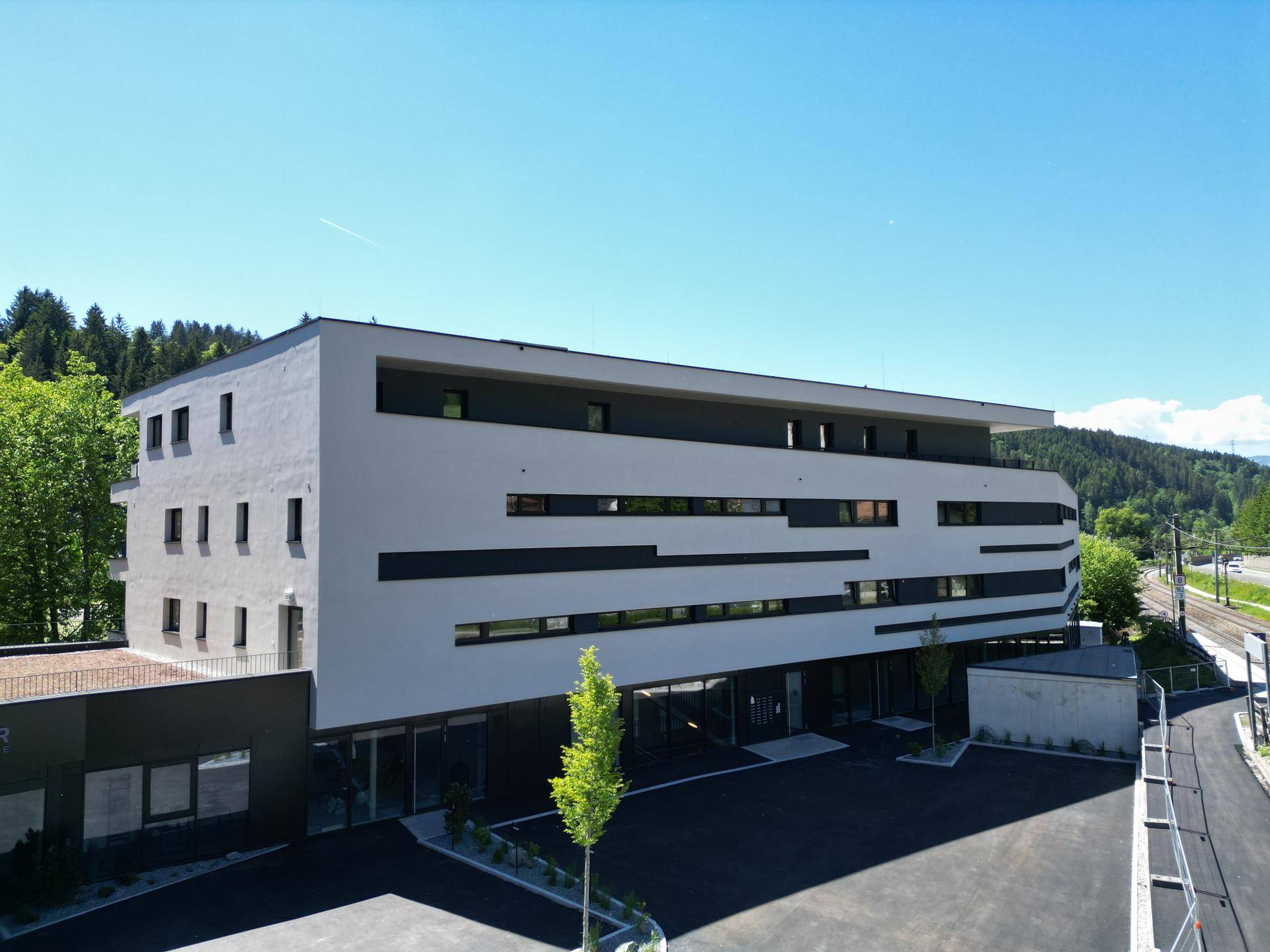 Modernes Gebäude bei Tageslicht mit klarer Architektur und umgebender Natur.