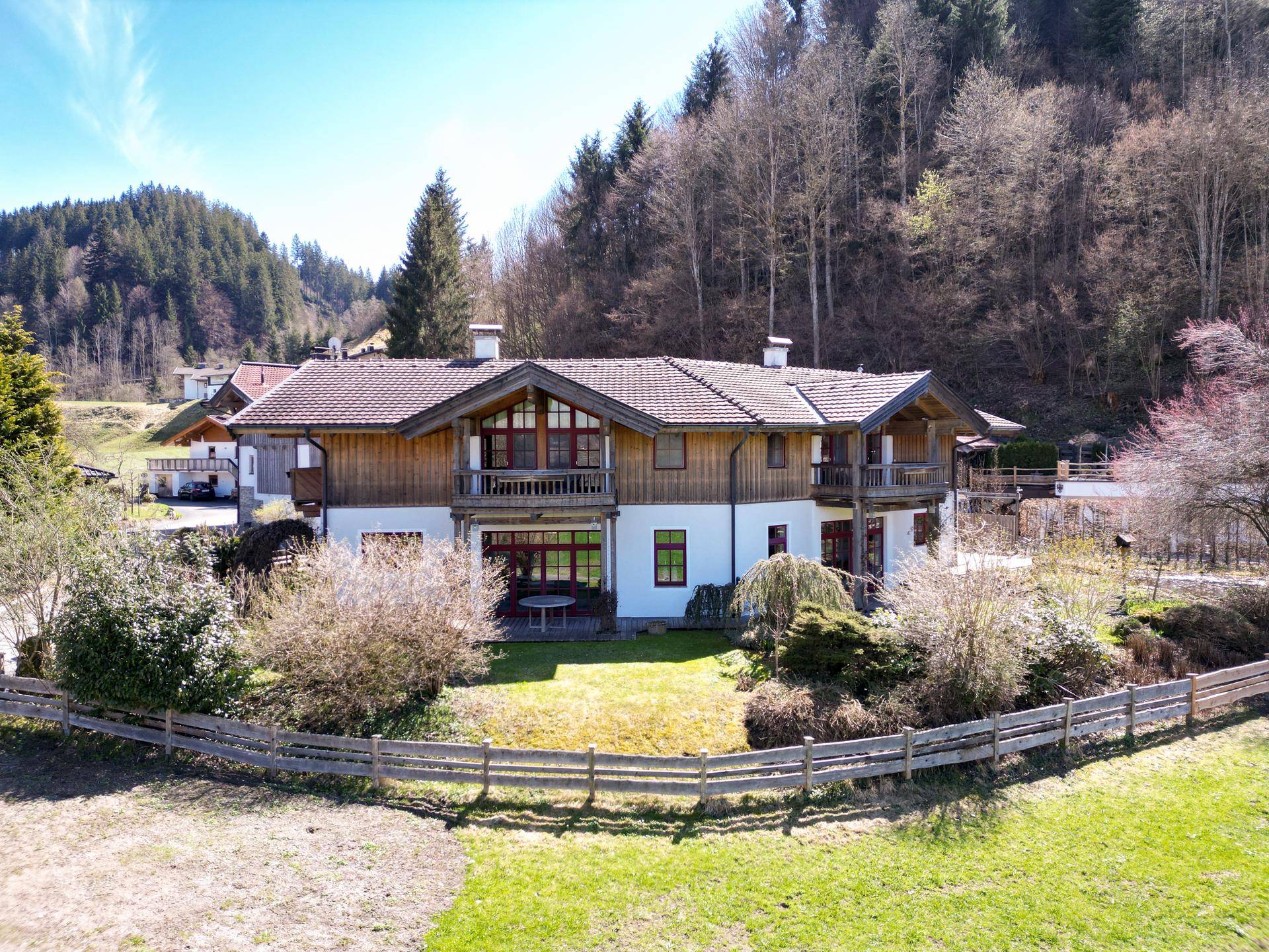 Weitläufige Ansicht des Landhauses in alpiner Umgebung mit grünen Wiesen und bewaldeten Hügeln.