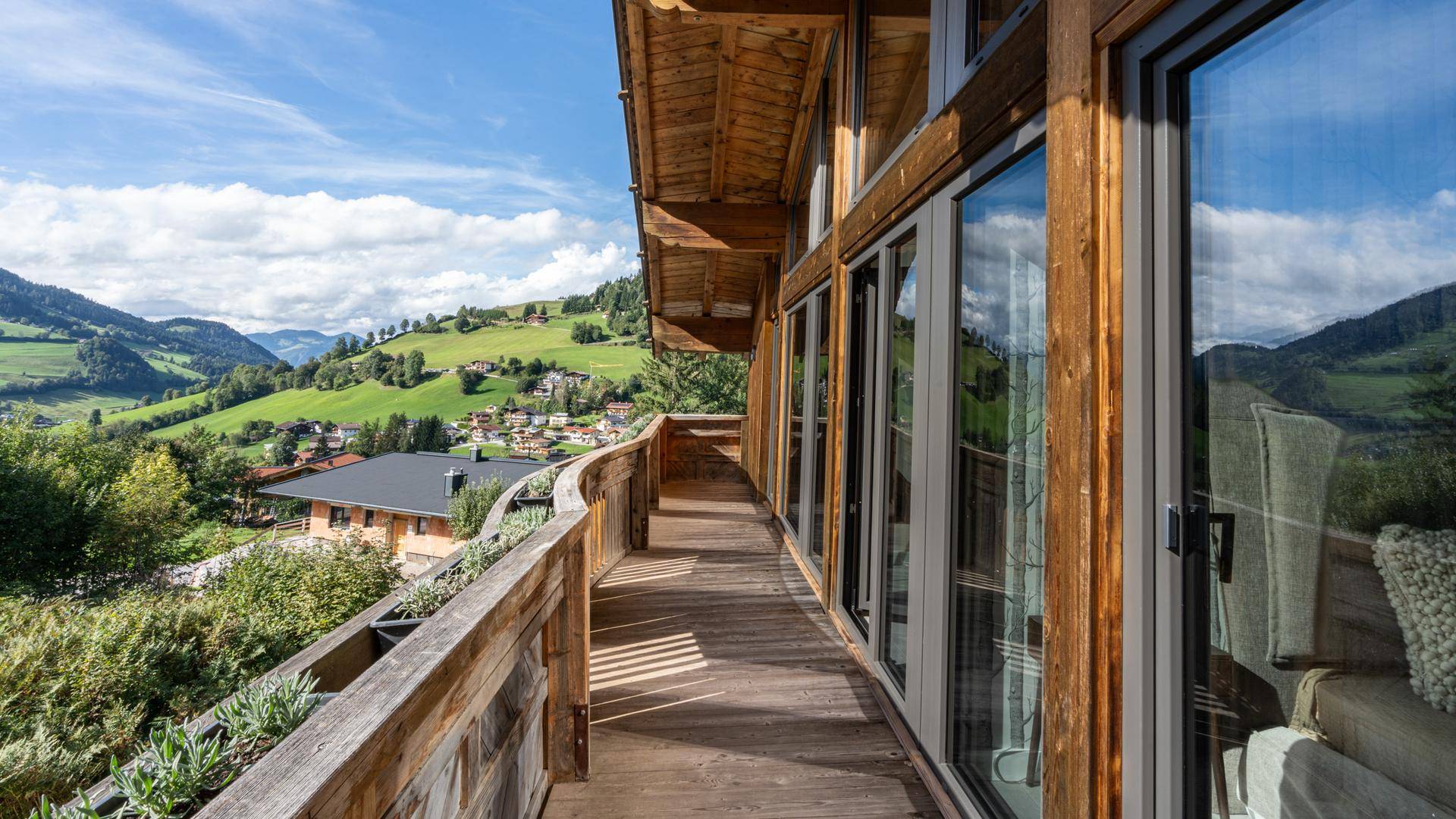 Langer Holzbalkon mit Panoramablick auf die grünen Berge und das malerische Tal.