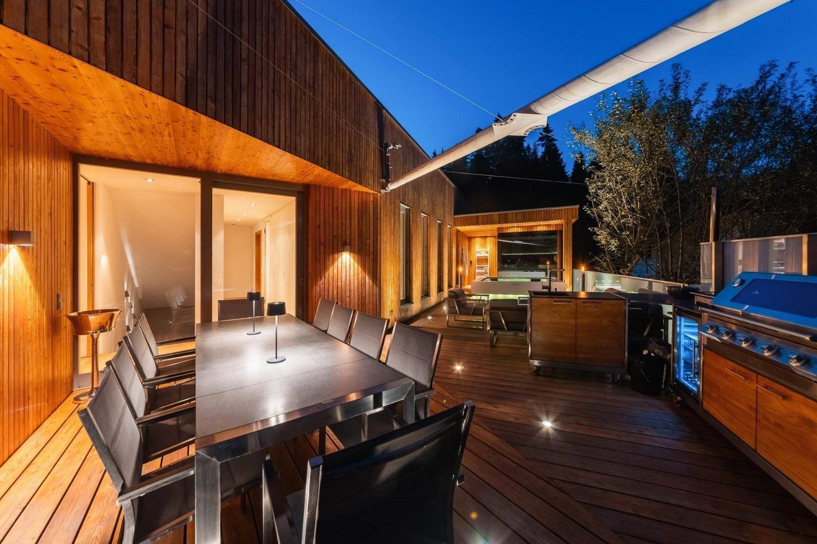 Geräumige Holzterrasse mit Grillbereich, Essplatz und Whirlpool für entspannte Abende.