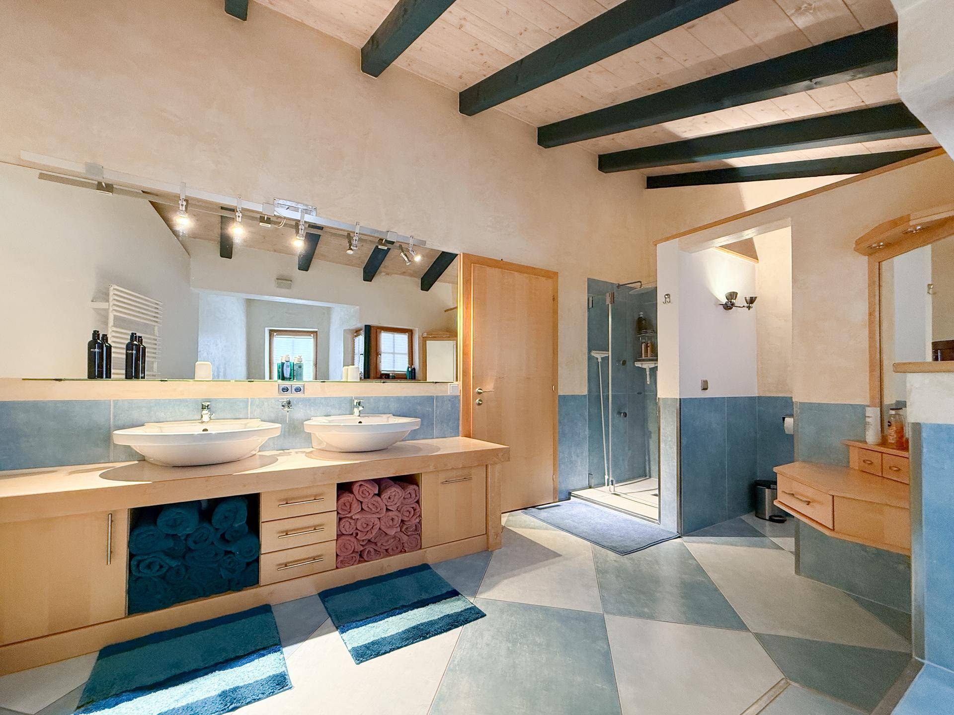 Geräumiges Badezimmer mit Doppelwaschbecken, begehbarer Dusche und Holzbalkendecke.