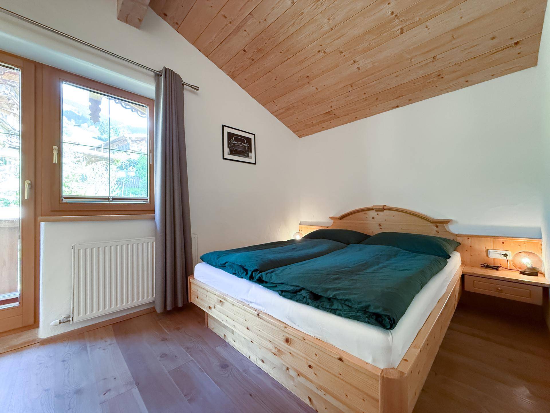 Helles Schlafzimmer mit Holzbett, Holzboden und Dachschräge.