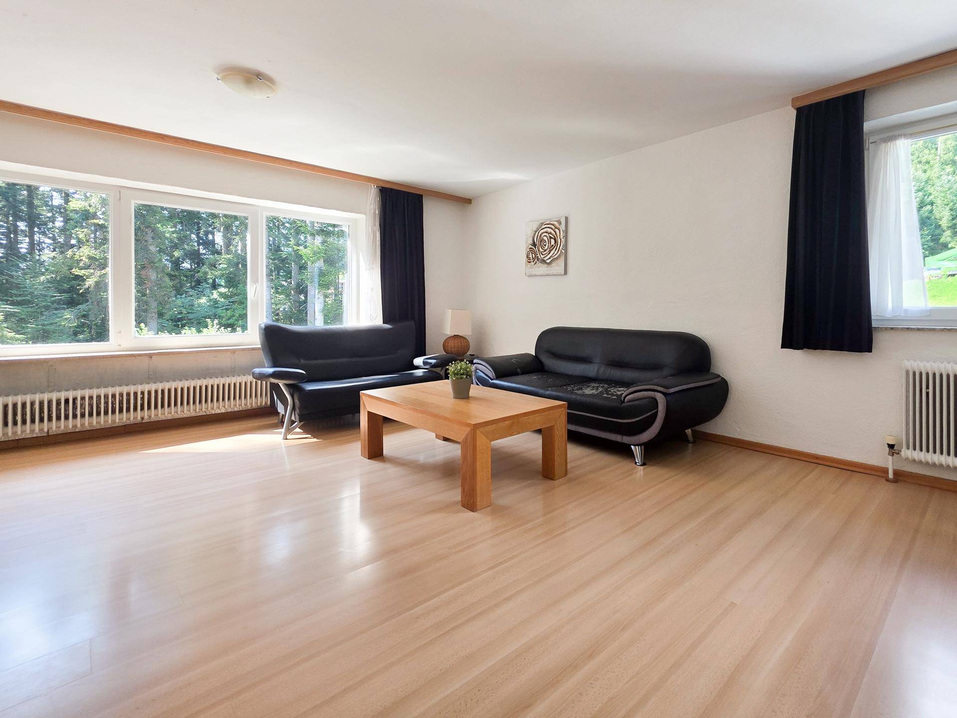 Helles Wohnzimmer mit großen Fenstern, die einen weiten Blick auf die umliegende Natur bieten.