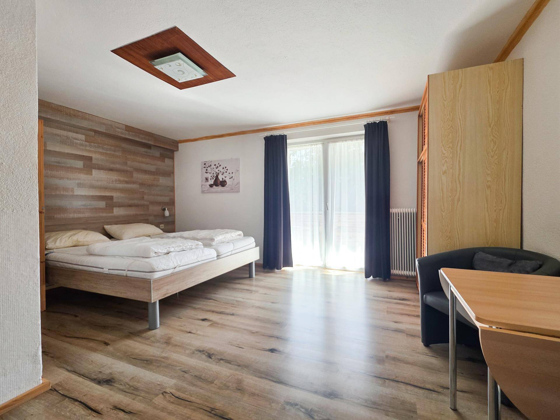 Gemütliches Schlafzimmer mit Doppelbett, Holzwandverkleidung und Zugang zu einem Außenbereich.
