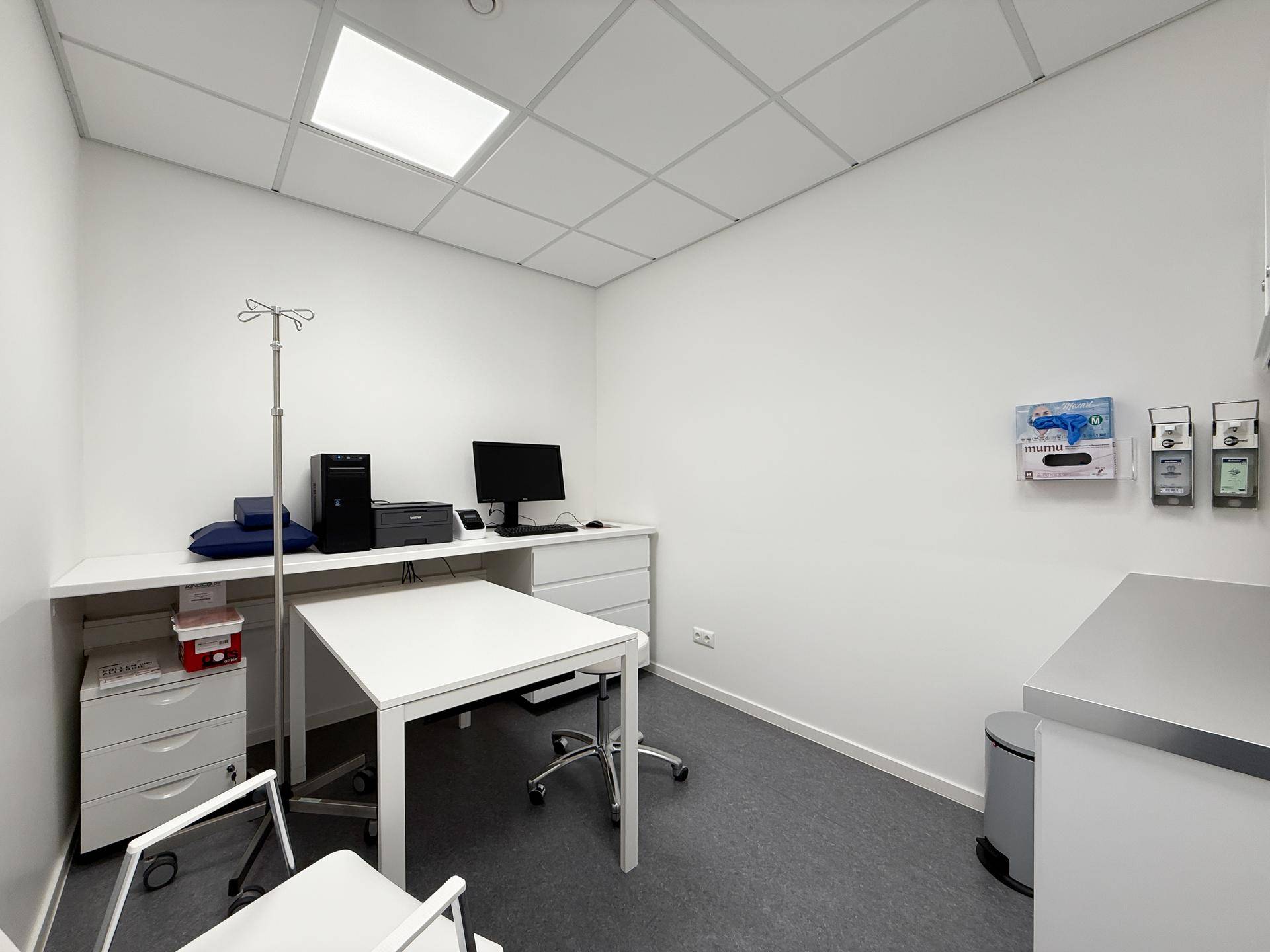 Funktionaler Büroraum mit Schreibtisch, Computer und zusätzlichem Tisch für Beratungen.