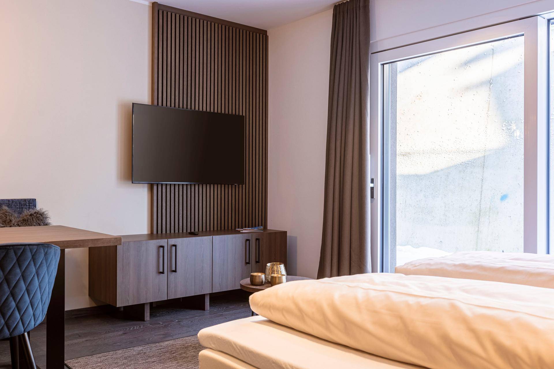 Schlafzimmer mit Einzelbetten, Fernseher und Holzvertäfelung, ideal für Gäste.