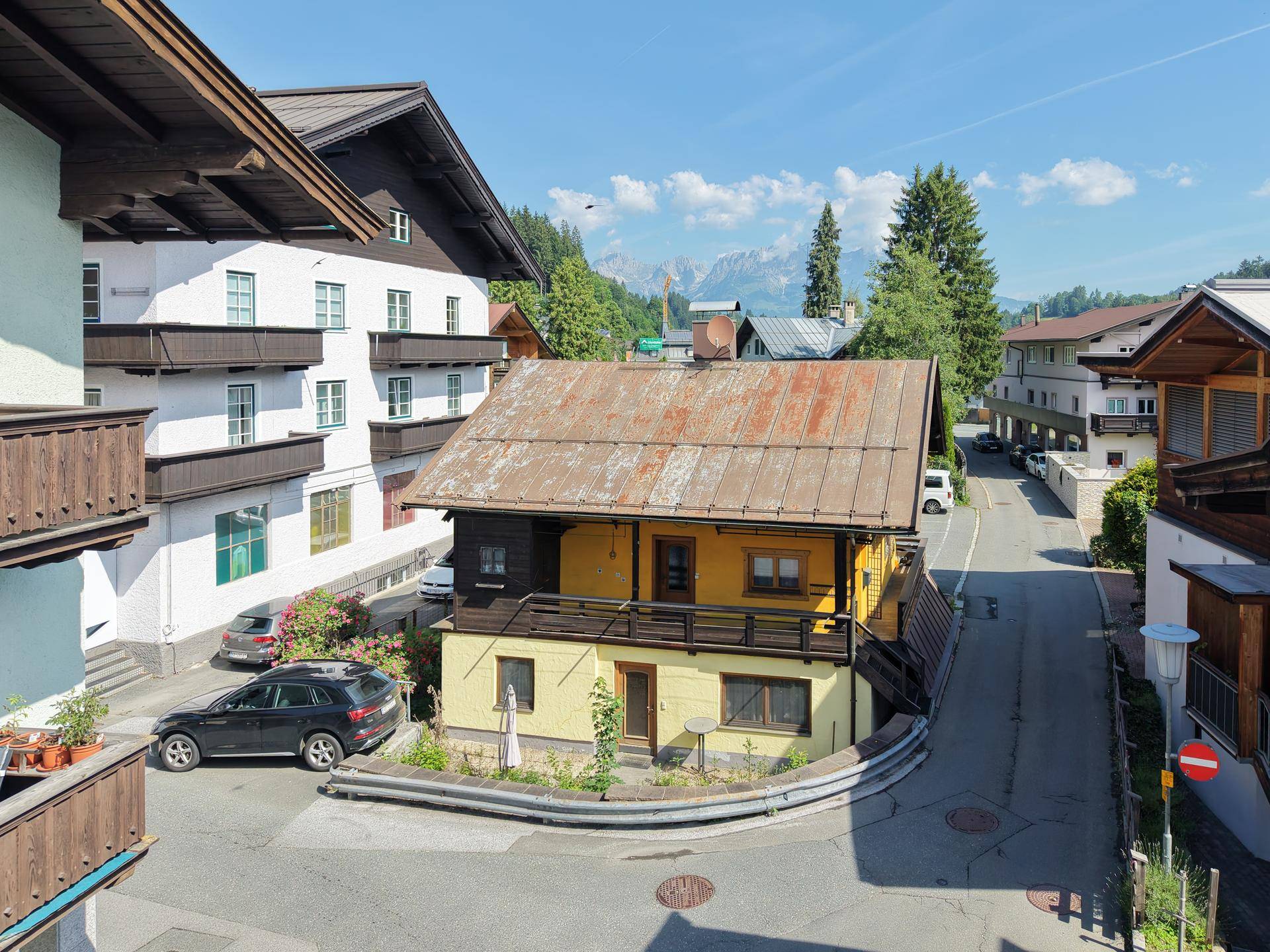 Traditionelles Gebäude mit gelber Fassade und Holzbalkonen in einer Berglandschaft.