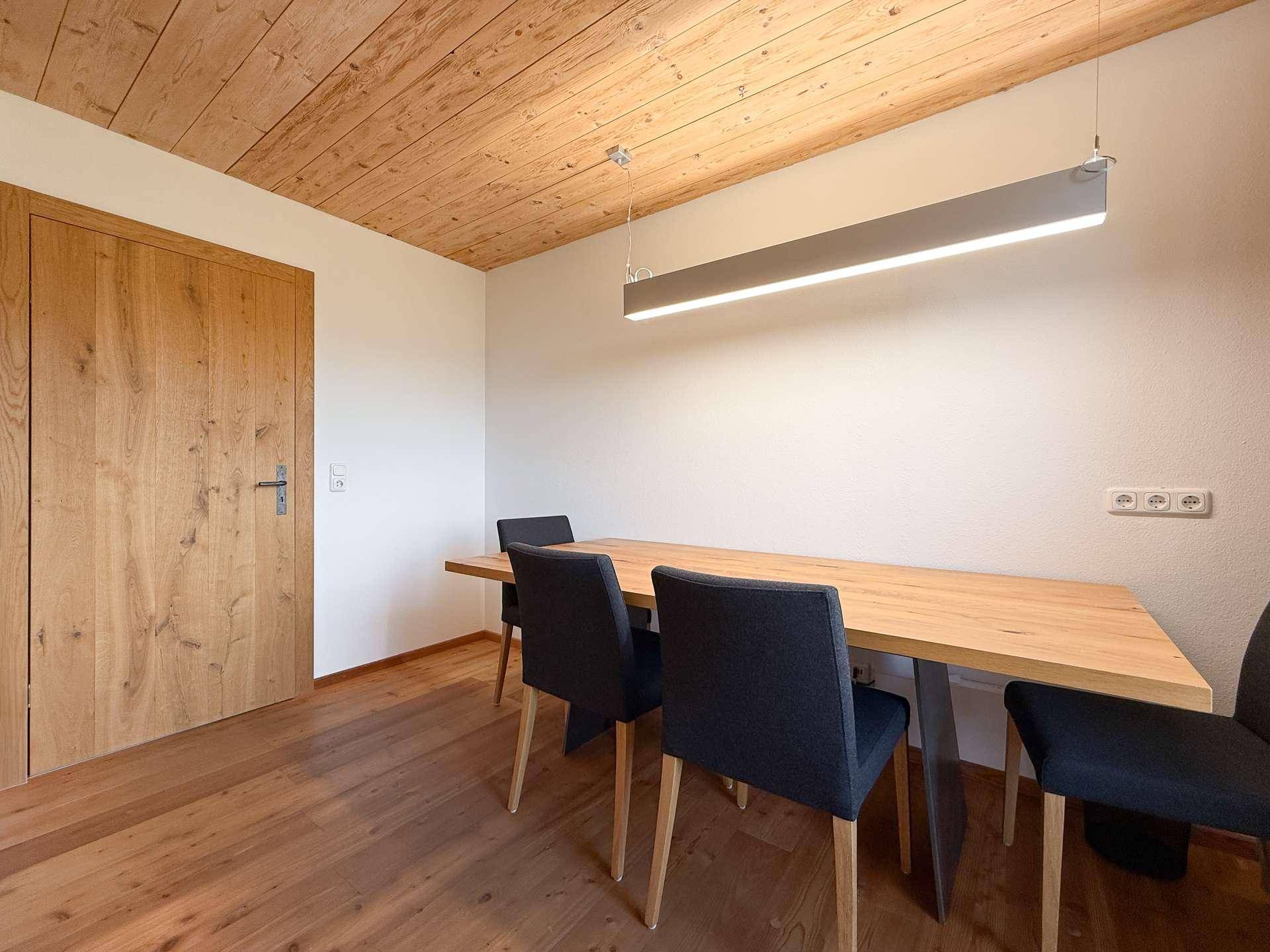 Heller Essbereich mit Holztisch, modernen Stühlen und Holzbalkendecke.