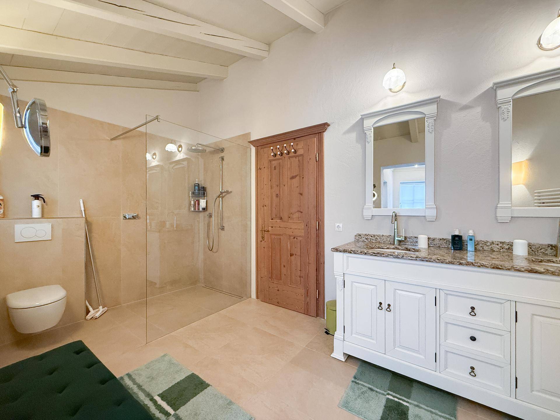 Großes Badezimmer mit Doppelwaschbecken, begehbarer Dusche und Granit-Arbeitsplatte.