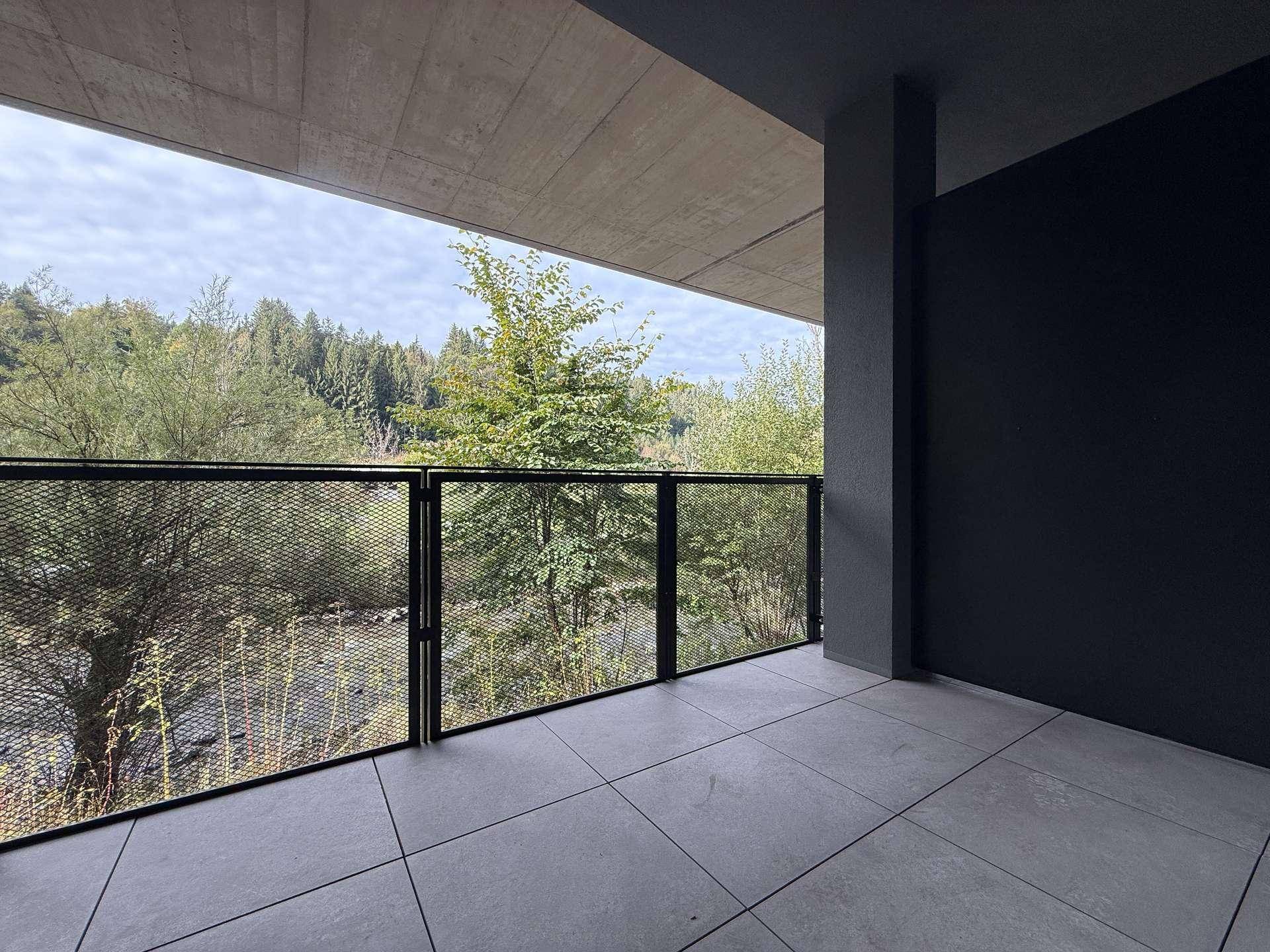 Überdachter Balkon mit Fliesenboden und Blick auf bewaldete Hügel und einen Fluss.