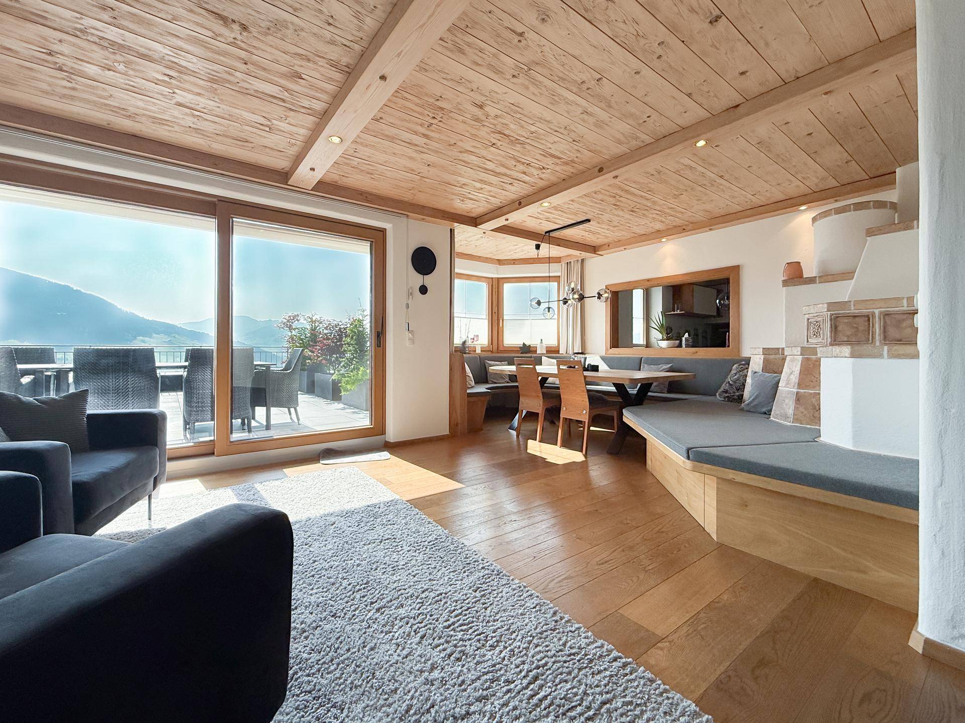 Geräumiger Wohn-Essbereich mit Holzboden, Kachelofen und Zugang zur Terrasse.
