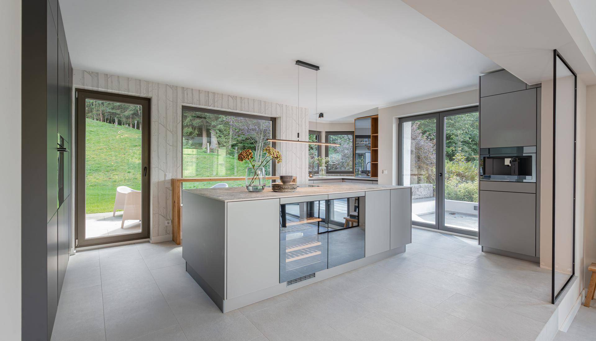 Helle, moderne Küche mit Kücheninsel, integrierten Geräten und Zugang zur Terrasse mit Bergblick.
