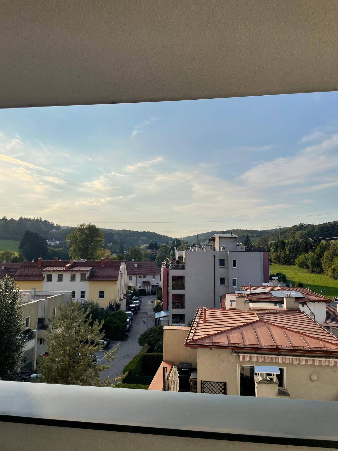 Panoramablick vom Balkon auf die umliegende Wohngegend und grüne Hügel.
