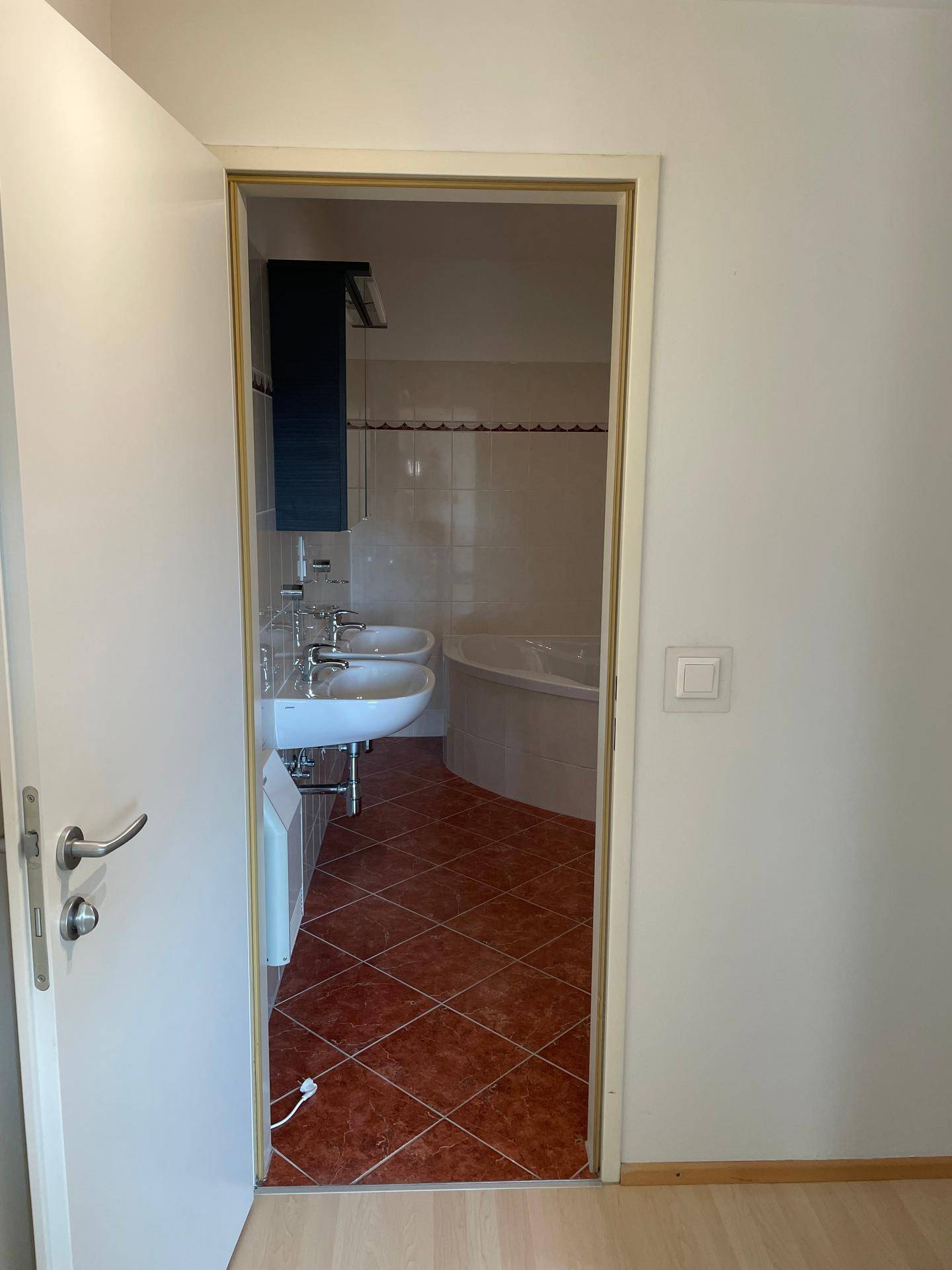 Blick in ein Badezimmer mit Doppelwaschbecken und einer Eckbadewanne.