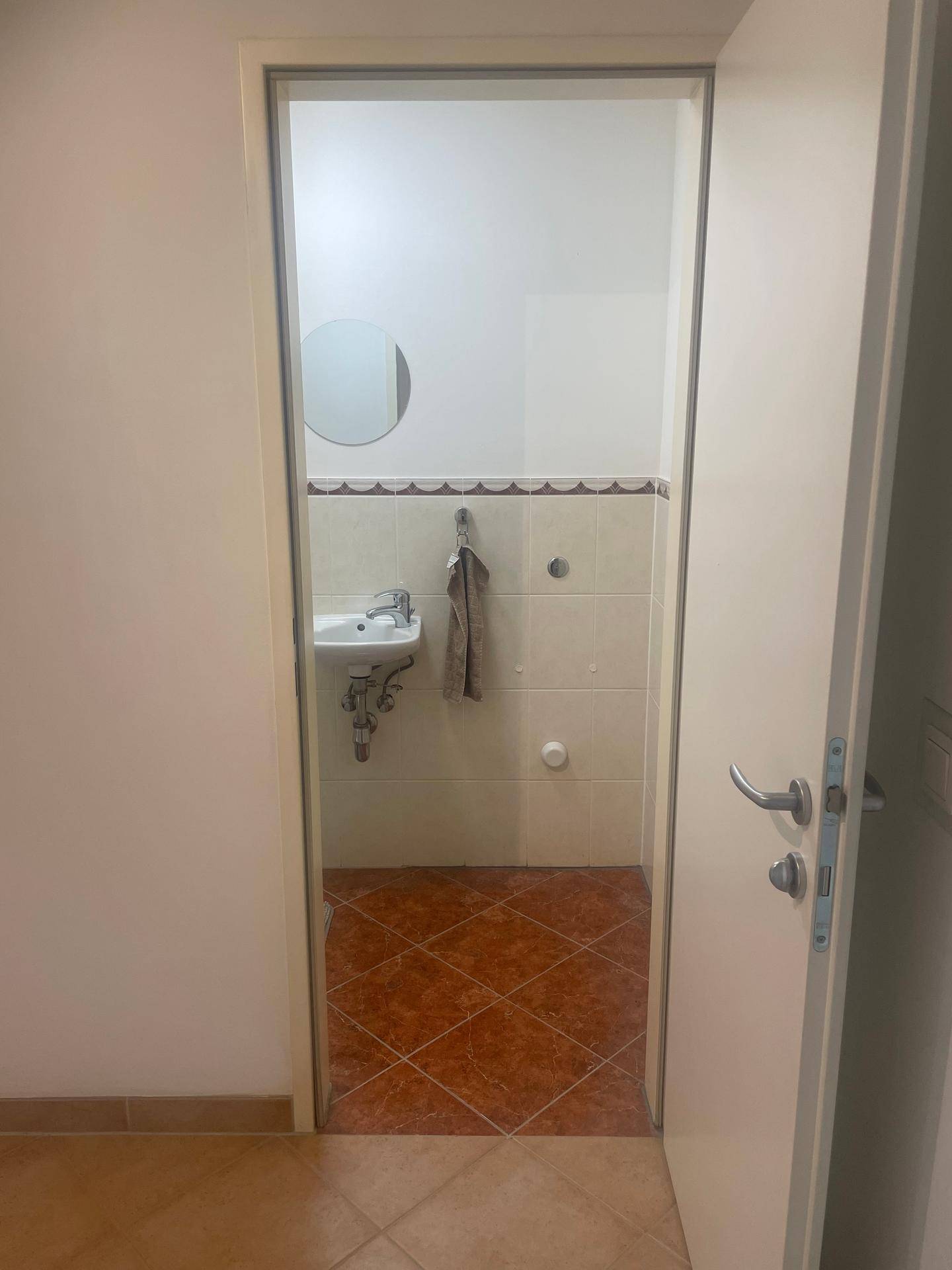 Blick in ein kleines Gäste-WC mit Waschbecken und hellen Fliesen.