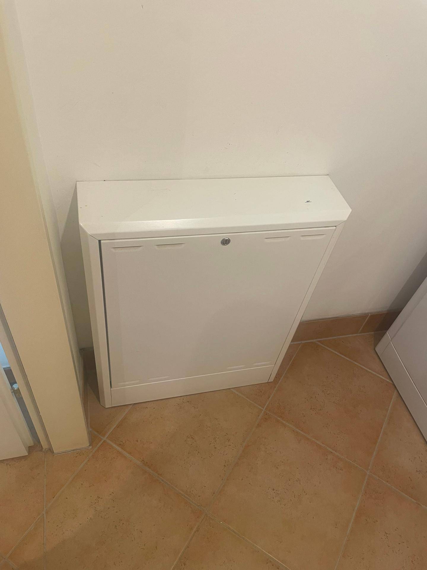 Weißer Wandschrank im Hauswirtschaftsraum mit Terrakotta-Fliesenboden.