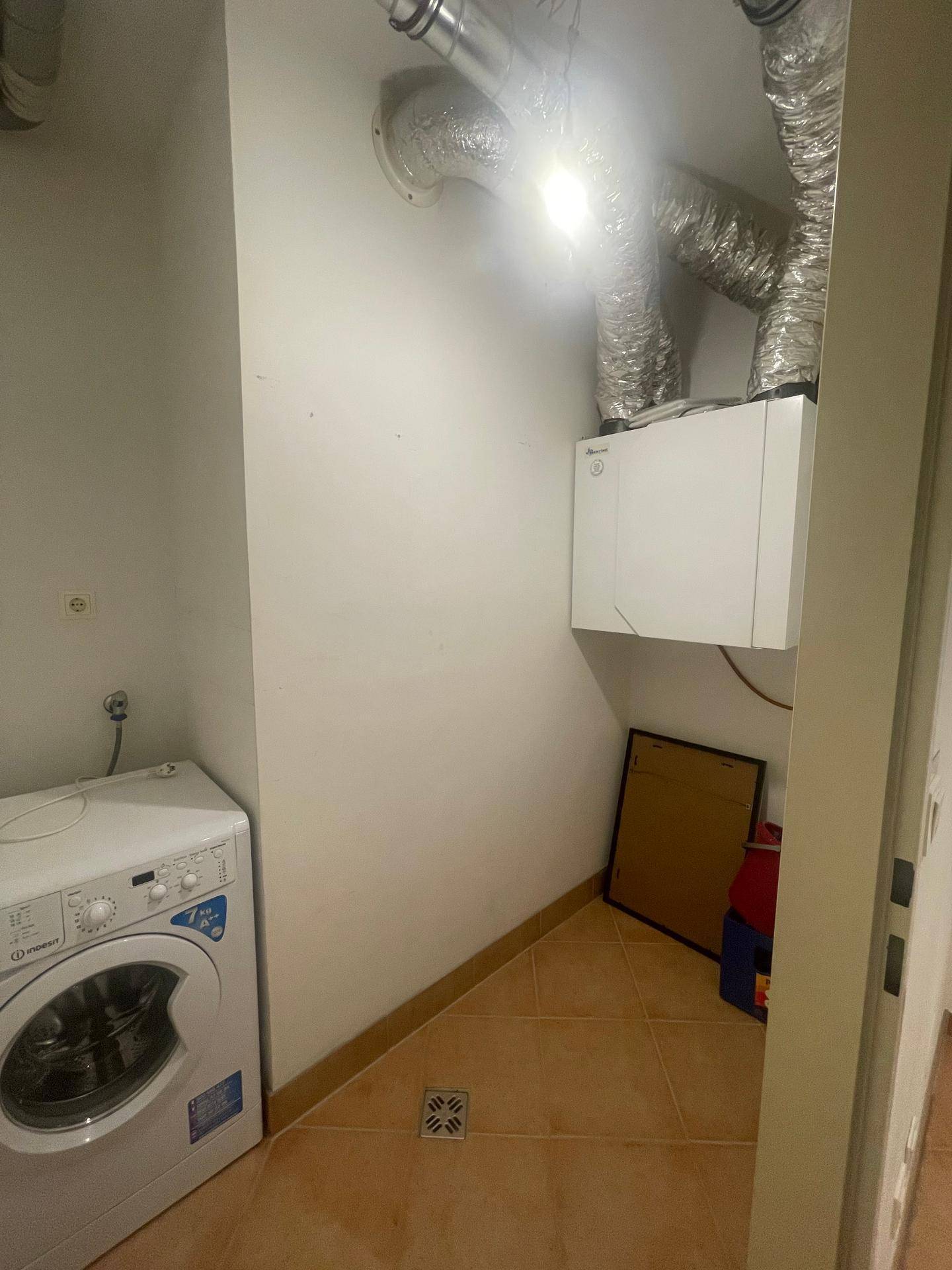 Hauswirtschaftsraum mit Waschmaschine, Lüftungsrohren und Heizungsanlage.