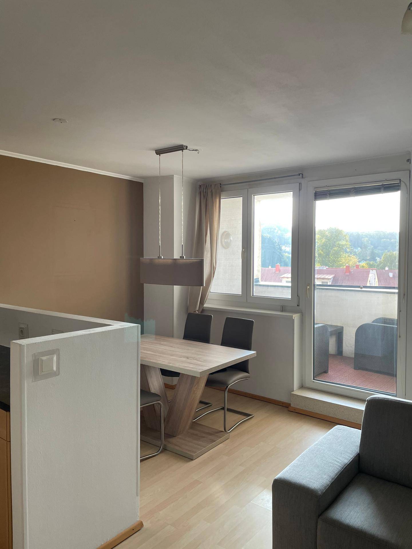 Offener Wohn-Essbereich mit Esstisch und Stühlen, sowie Zugang zum Balkon.