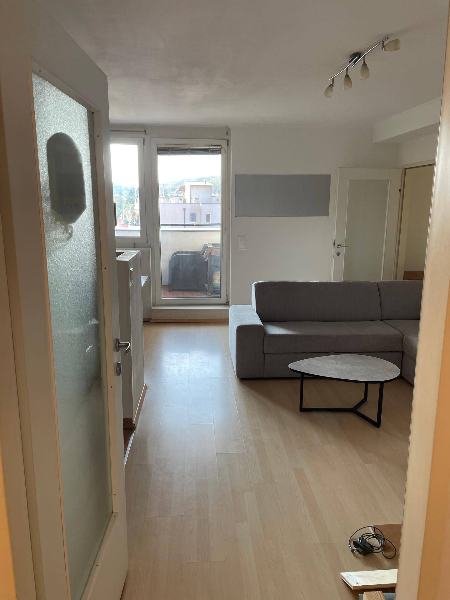 Helles Wohnzimmer mit Sofa, Couchtisch und Zugang zum Balkon.