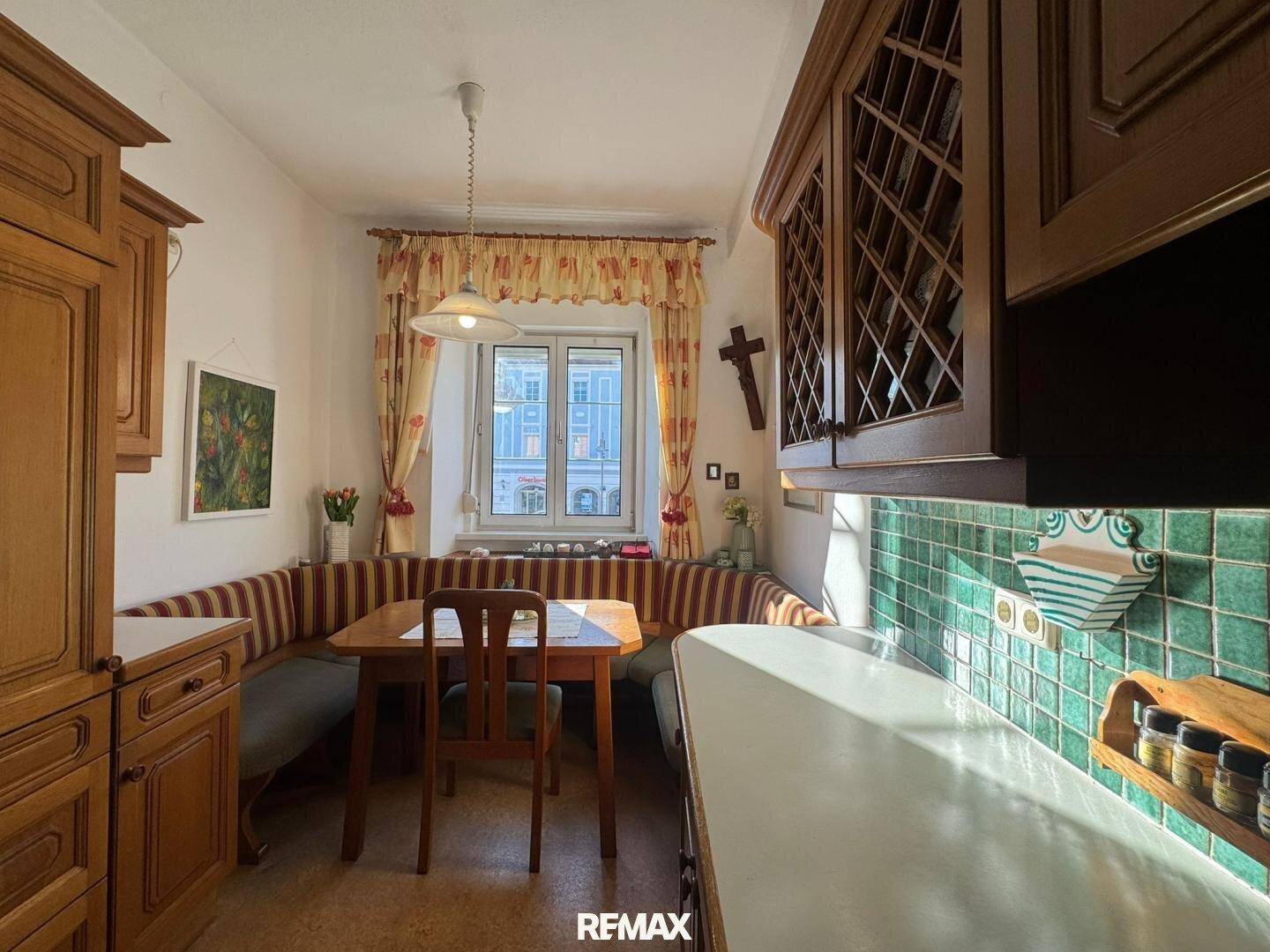 Traditionelle Küche mit Holzeinbauten, Essbereich und Blick auf die Stadt durch das Fenster.