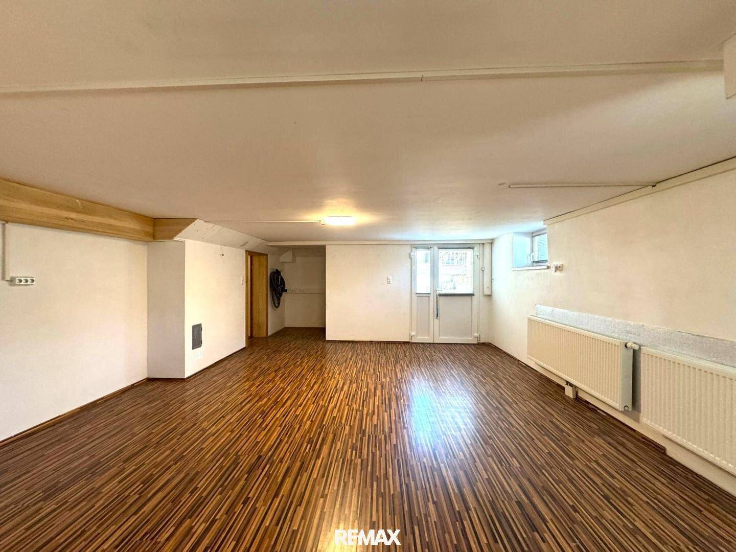 Geräumiger Kellerraum mit Laminatboden und Heizkörpern, vielseitig nutzbar.
