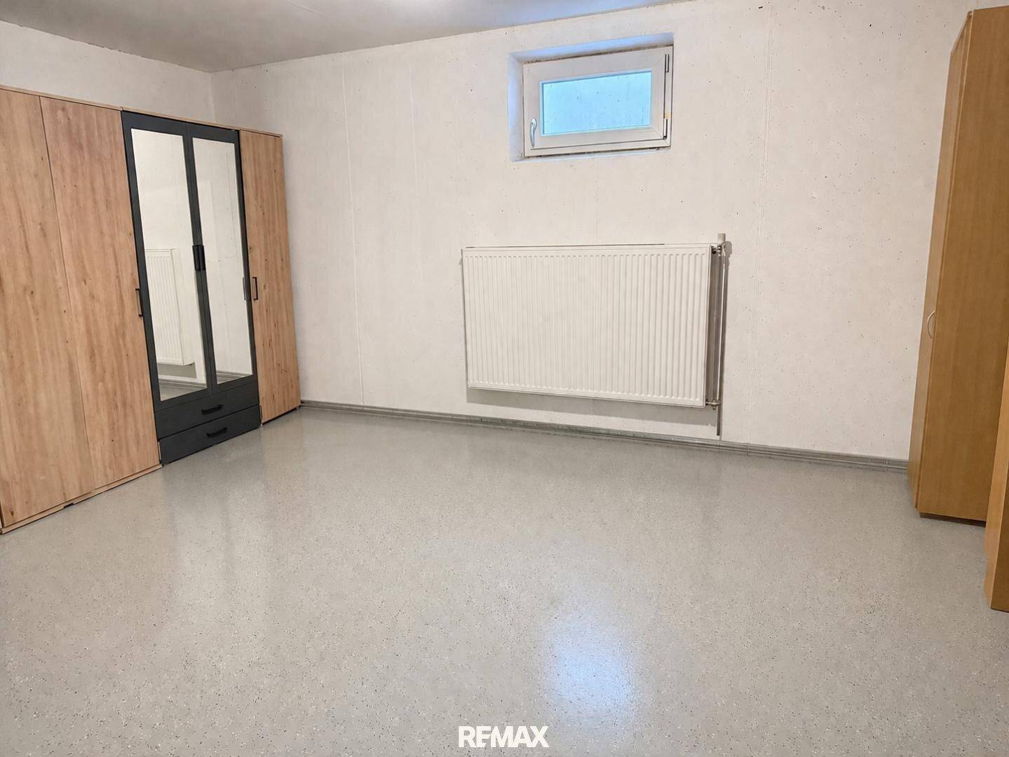 Geräumiger Kellerraum mit Fenster, Heizkörper und Schränken für Stauraum.