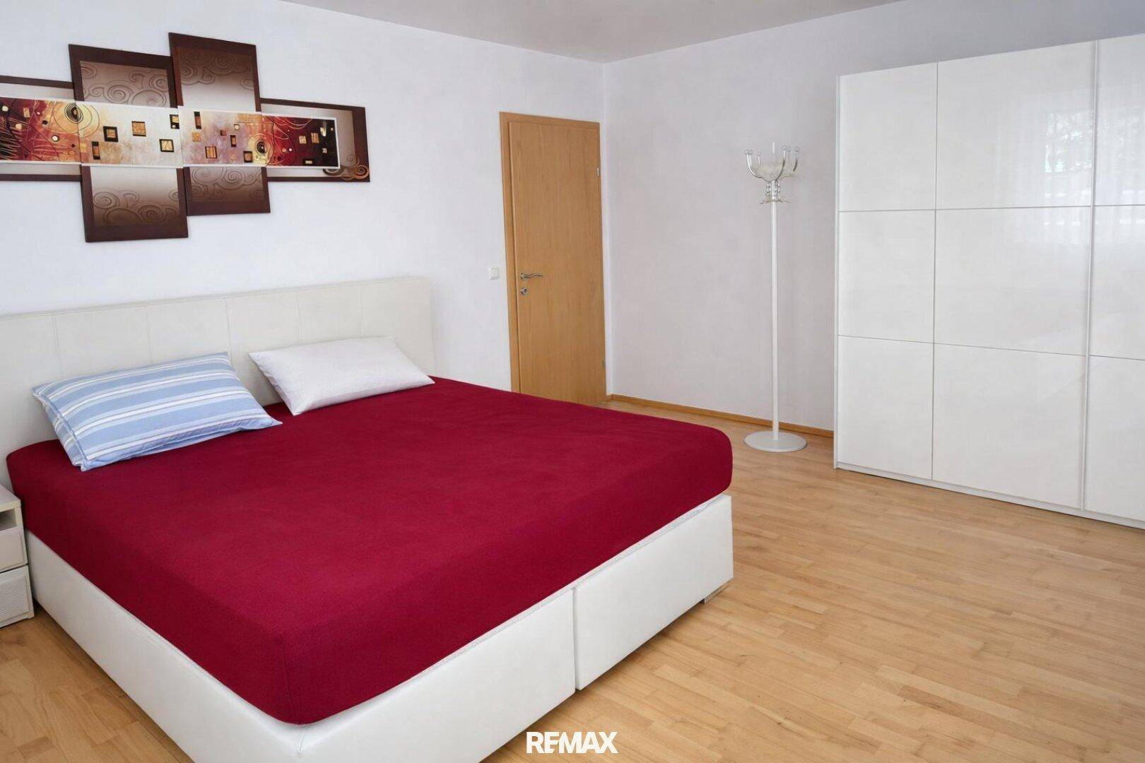 Gemütliches Schlafzimmer mit Doppelbett, weißem Kleiderschrank und Holzboden.
