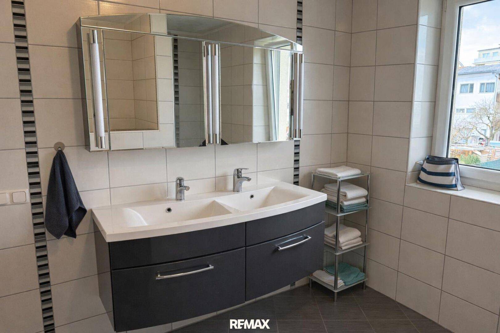 Modernes Badezimmer mit Doppelwaschbecken, Spiegelschrank und Fliesenboden.